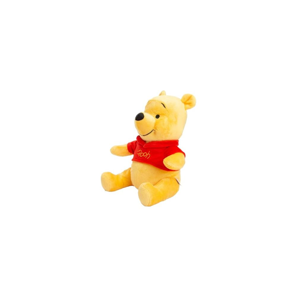 Un ours en peluche jaune portant une chemise rouge est assis.