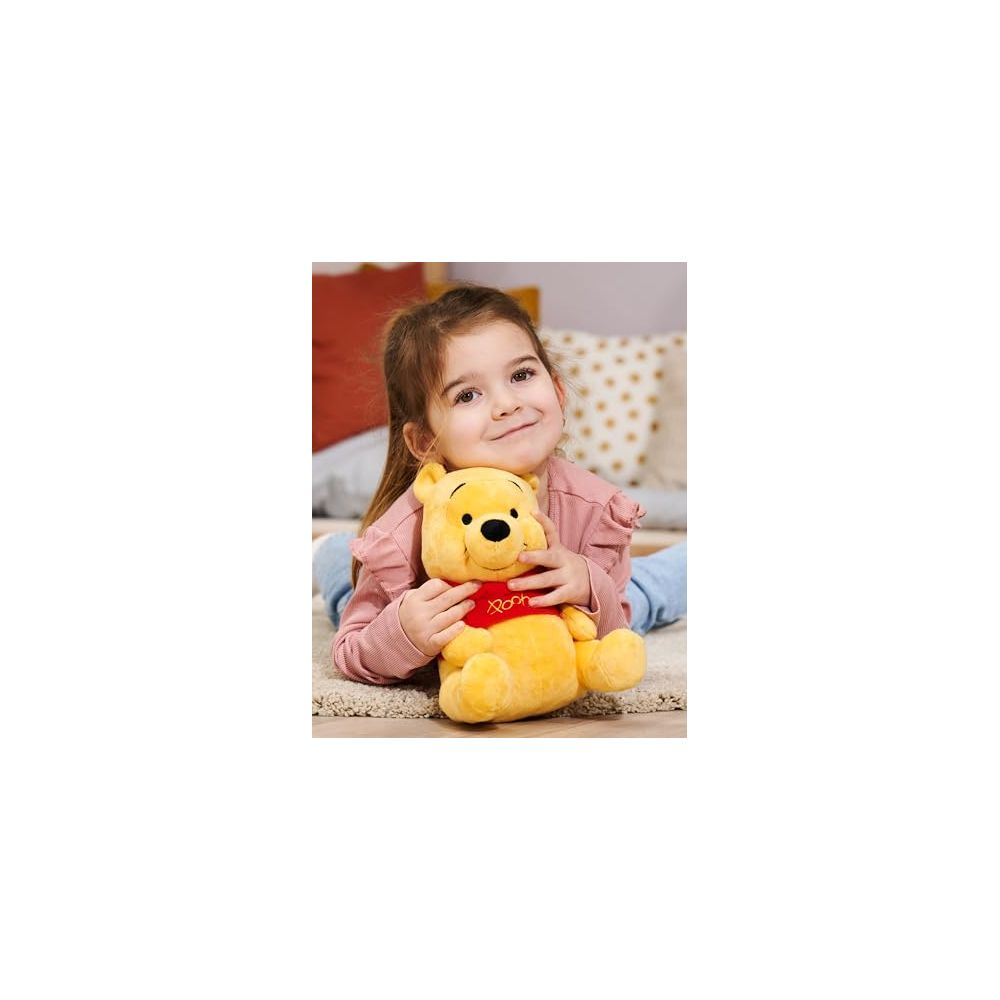 Une jeune fille est allongée sur le ventre, serrant une peluche Winnie l'Ourson.