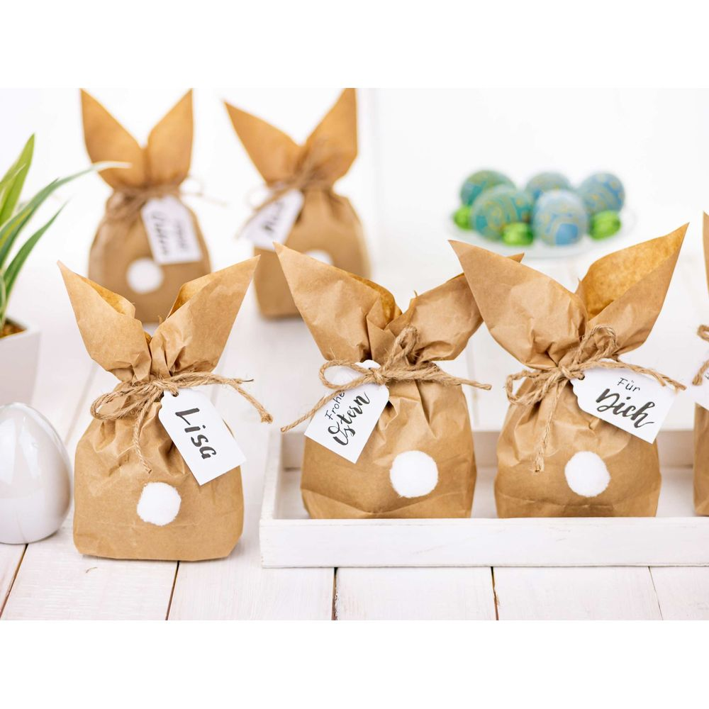 Sacchetti regalo marroni a coniglietto pasquale con pompon bianchi e etichette.