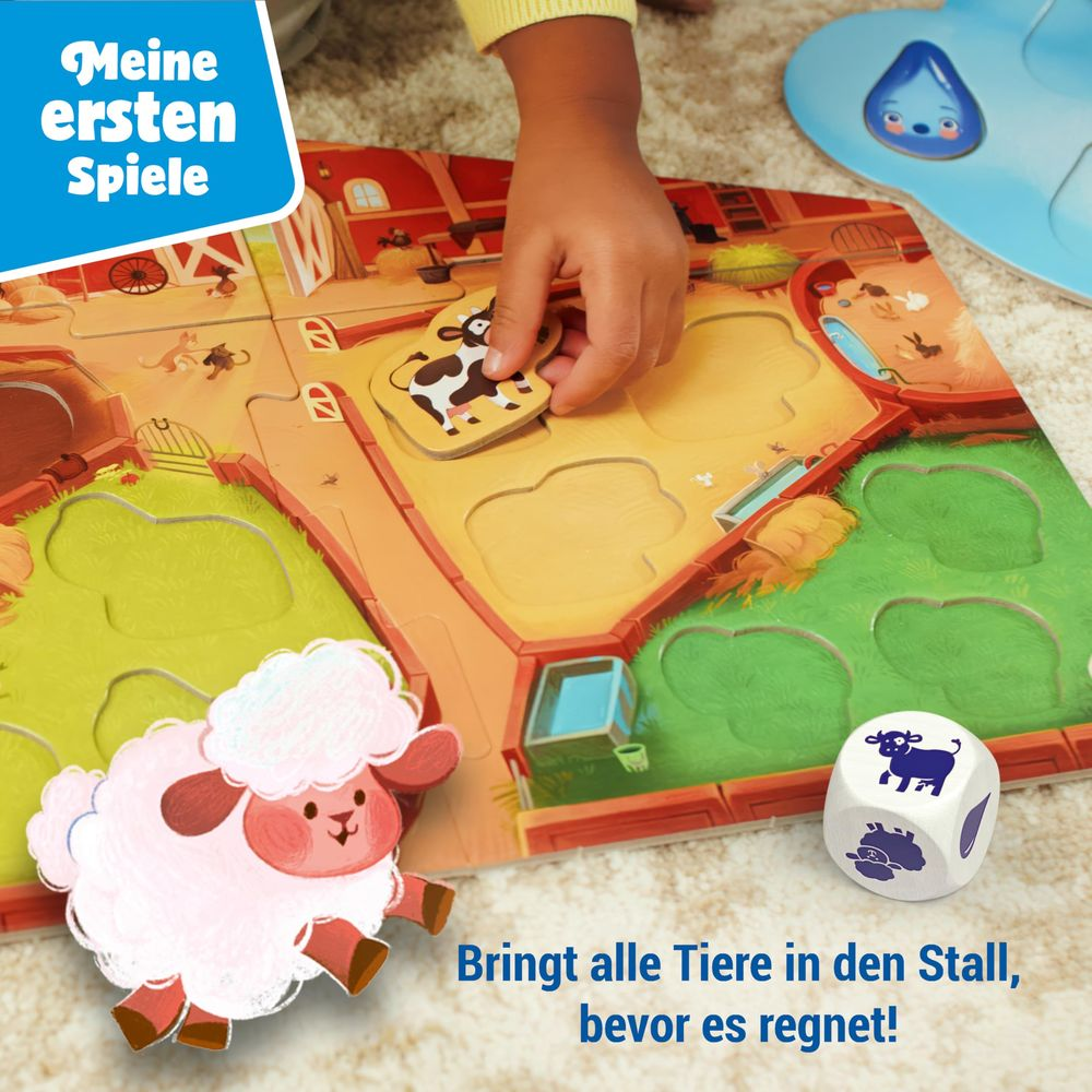Kind legt Kuh-Puzzle auf Bauernhof-Spielbrett. Schaf-Figur und Würfel liegen daneben.