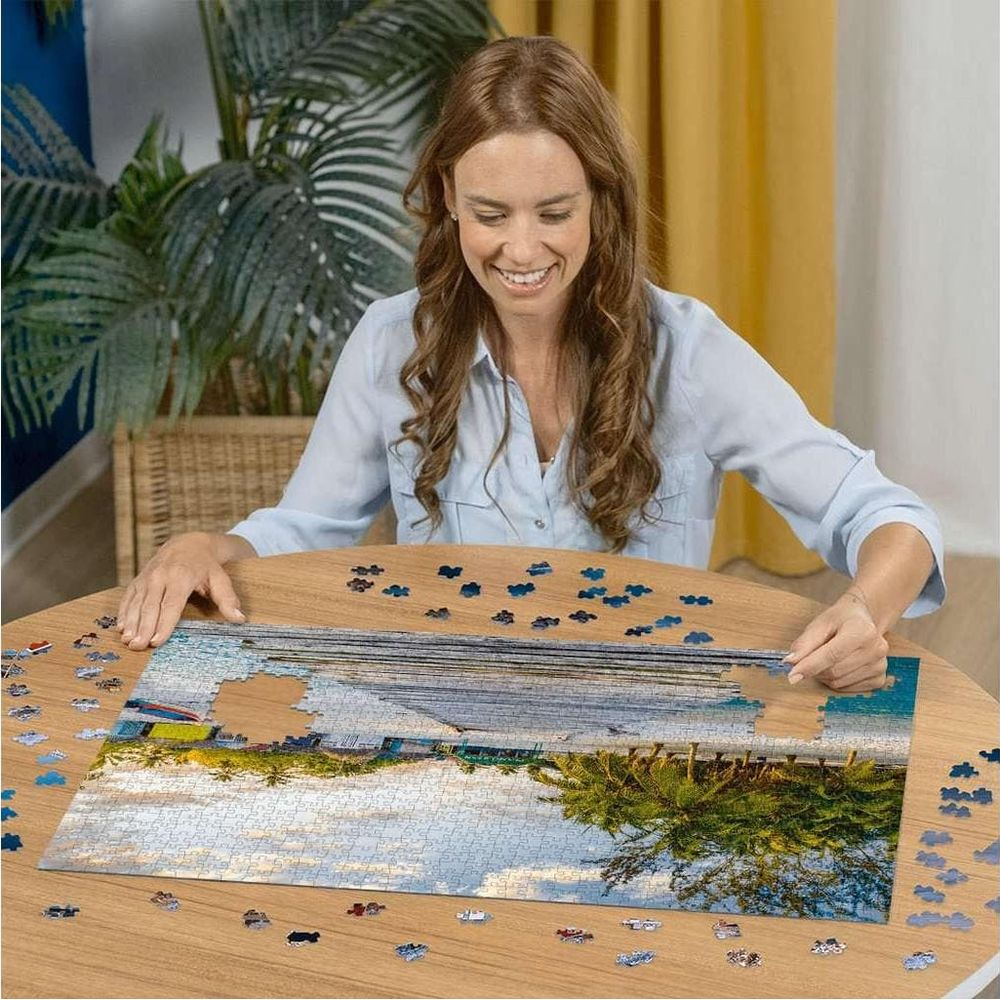 Donna che assembla un puzzle di una scena da spiaggia con edifici colorati.