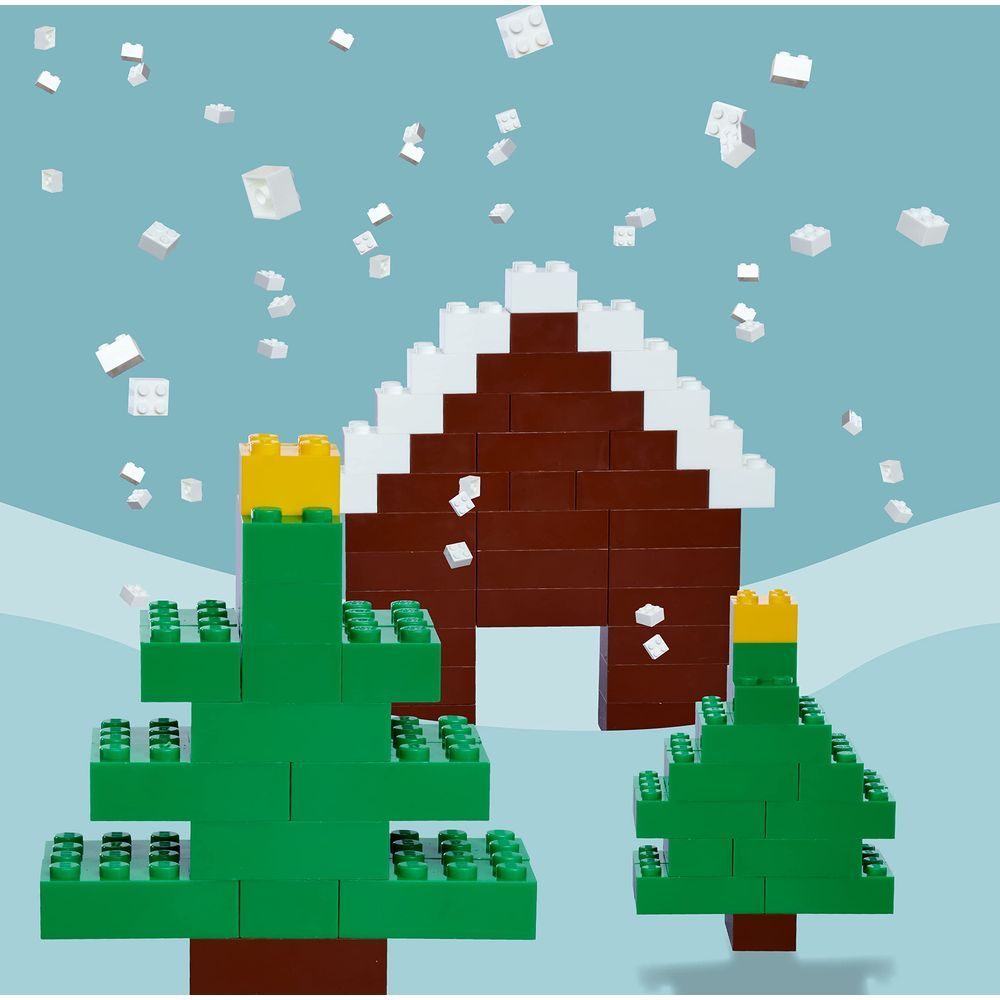 Blocchi colorati formano una casa con neve e due alberi di Natale.