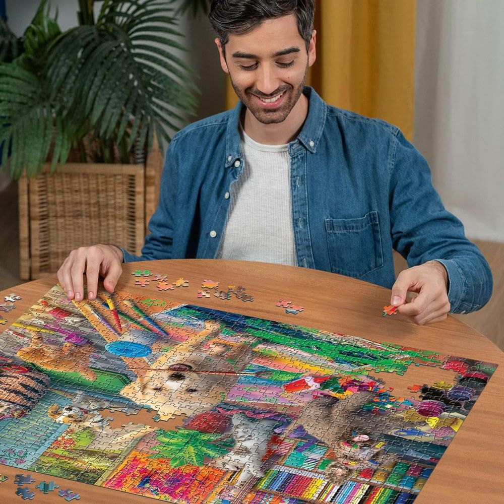 Un uomo siede a un tavolo di legno assemblando un puzzle raffigurante gatti e matite colorate.