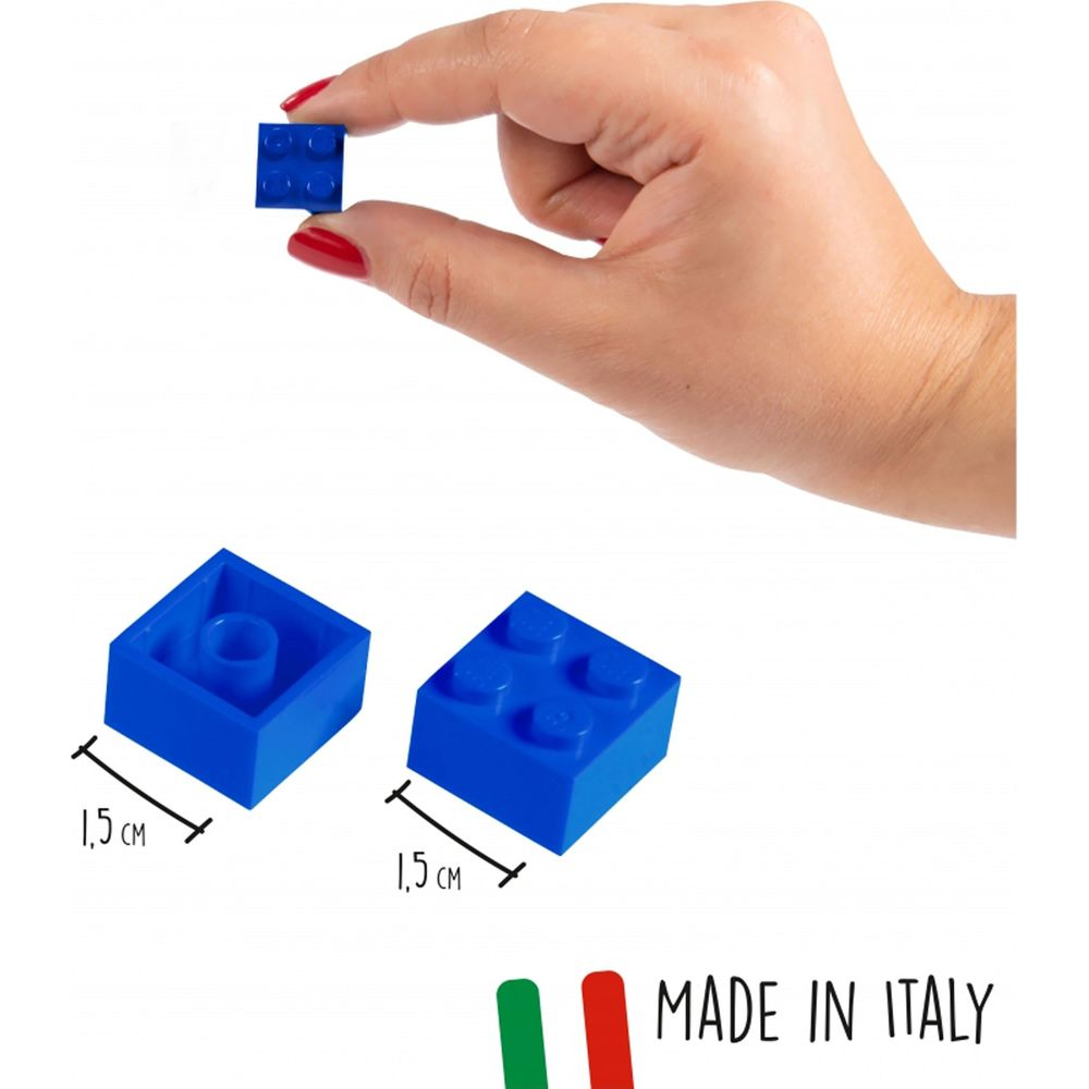 Una mano tiene un piccolo mattoncino blu. Due altri giacciono accanto.