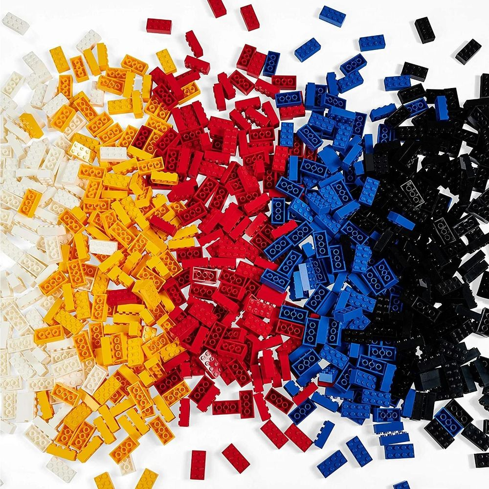 Briques de construction colorées dispersées sur fond blanc.