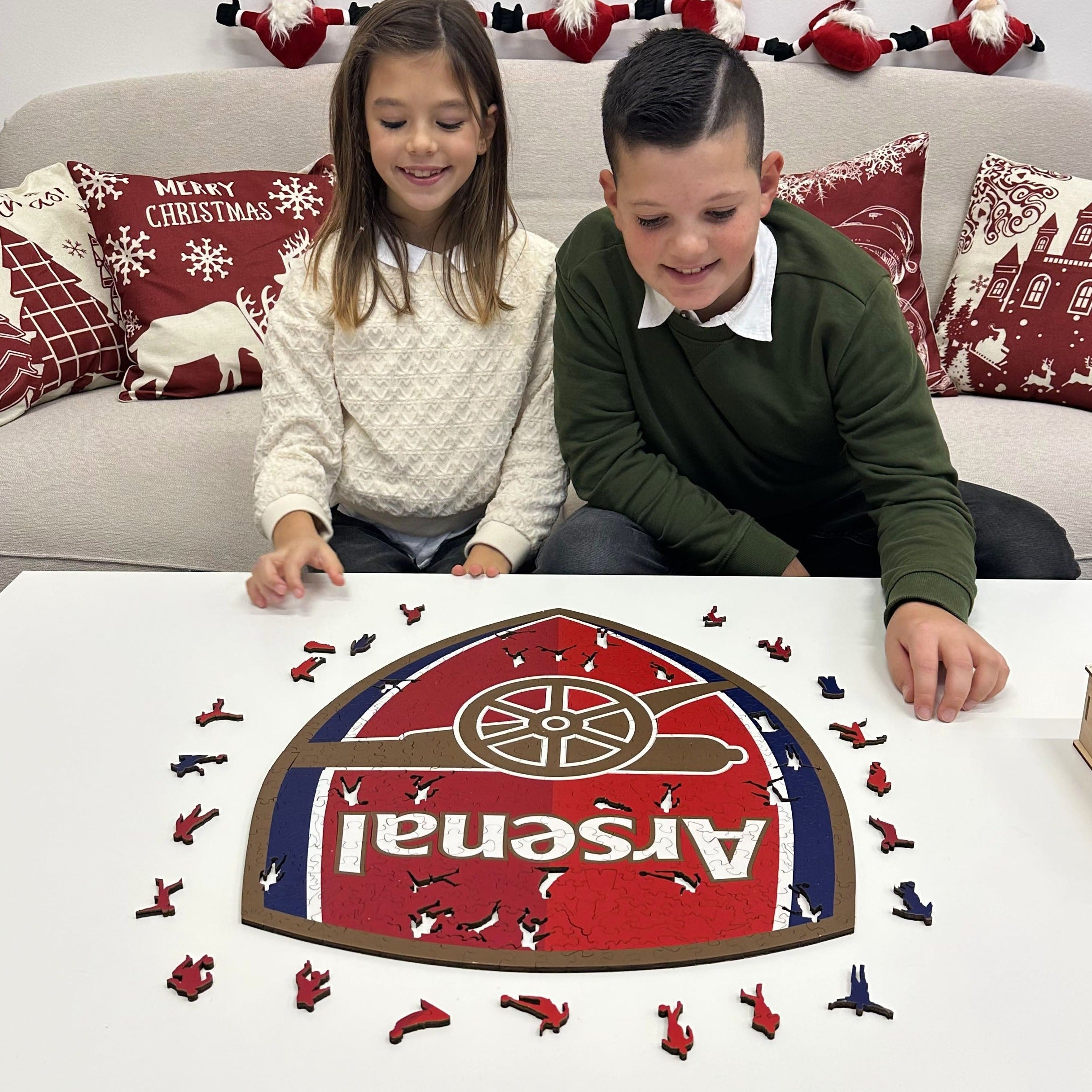 Zwei Kinder bauen ein Arsenal-Puzzle mit roten und blauen Spielfiguren.