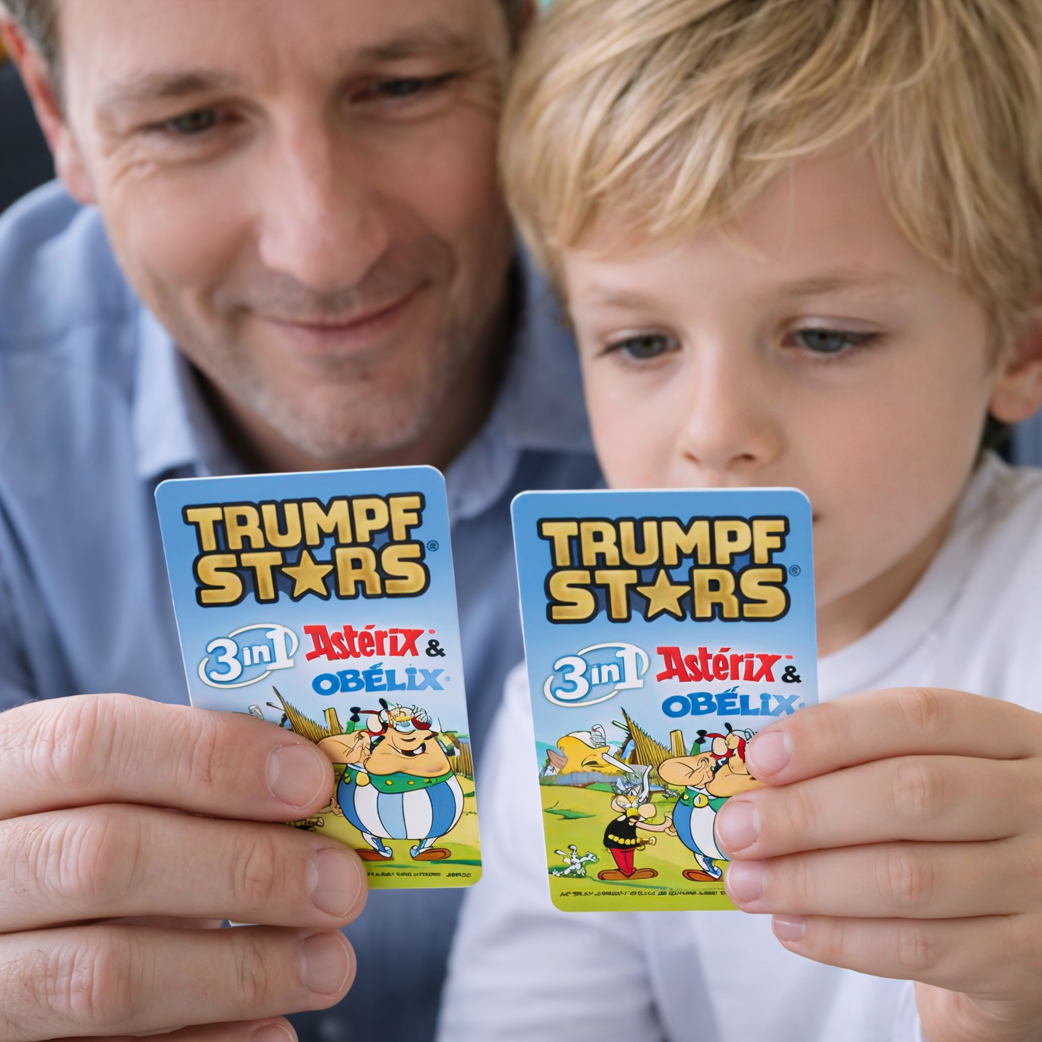 Mann und Kind halten Karten mit Asterix und Obelix.