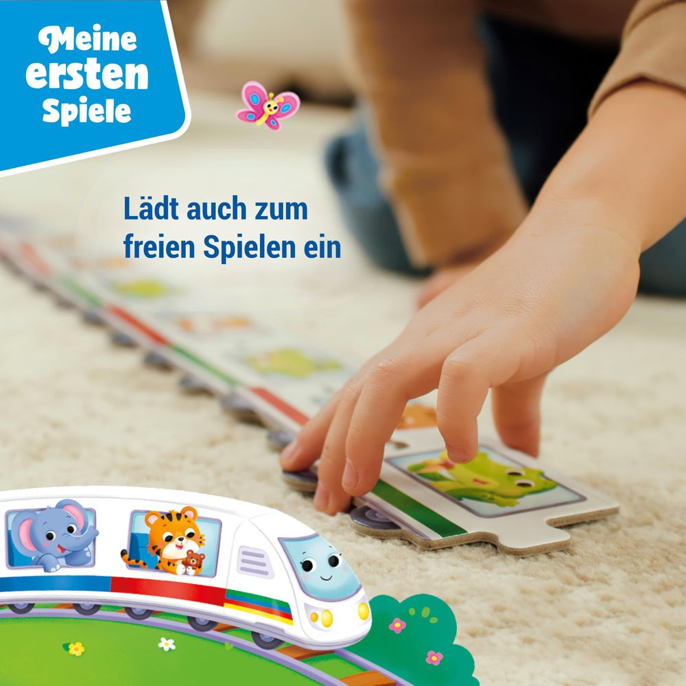 Kind spielt mit Zug-Puzzle auf Teppich. Schmetterling fliegt.
