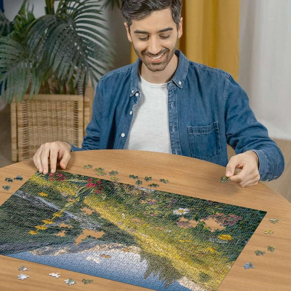 Un homme joue à un puzzle sur le thème des fleurs. Il est assis à une table en bois.
