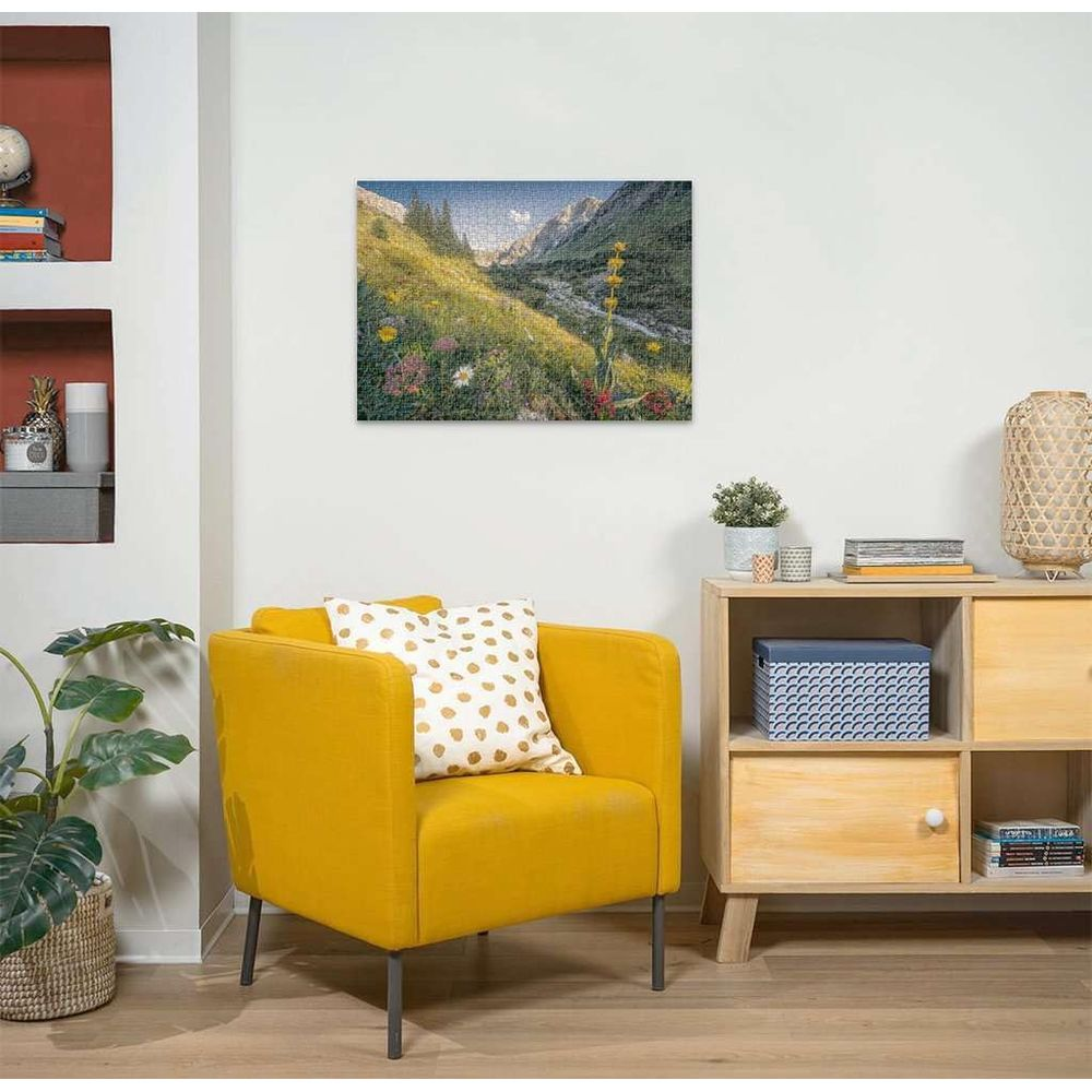 Un fauteuil jaune avec coussin devant une armoire. Un puzzle de vallée de montagne accroché au mur.