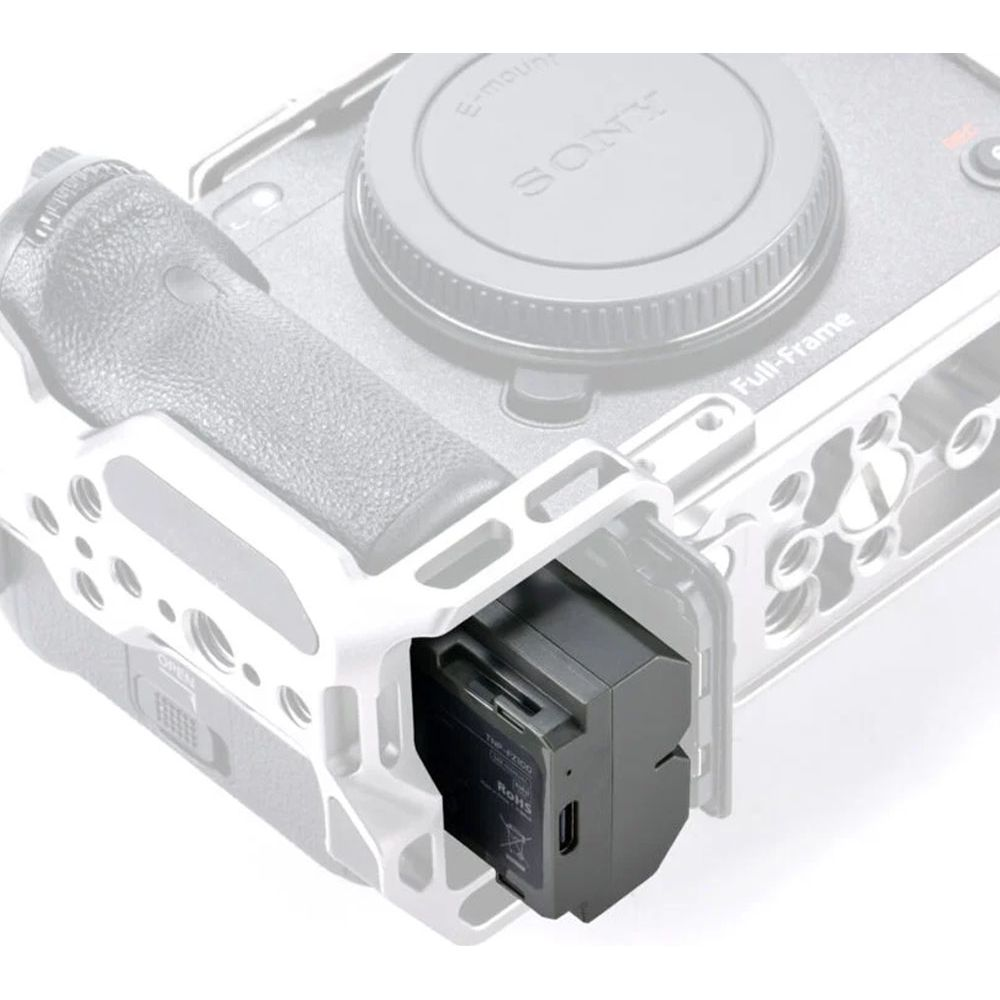 Una gabbia per fotocamera grigia con una batteria nera parzialmente inserita.