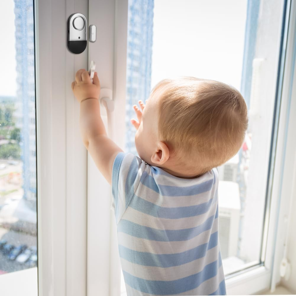 Ein Kleinkind in gestreiftem Oberteil greift nach einem Fenstergriff, ein Alarmsensor ist angebracht.