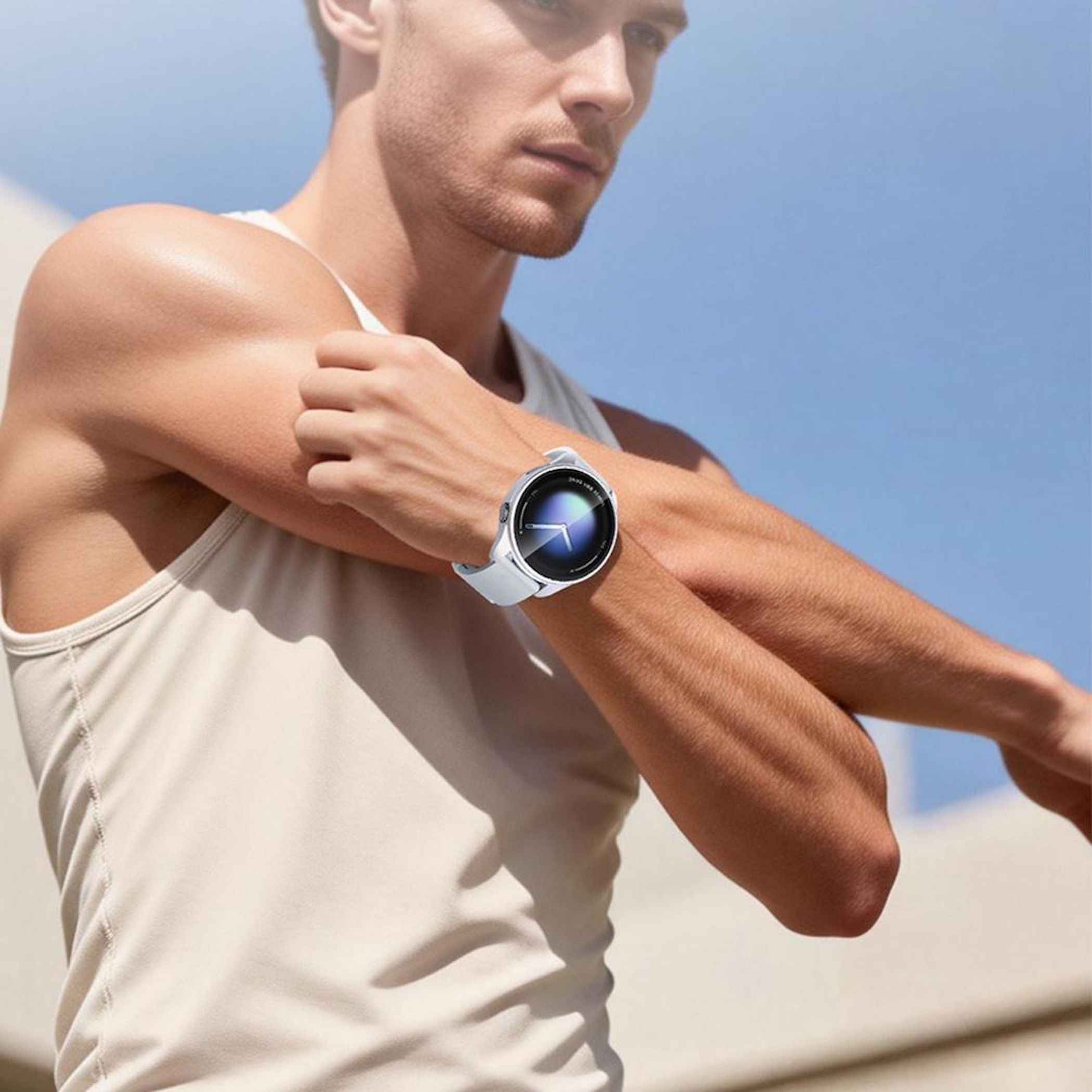 Uomo con smartwatch al polso che fa esercizio, cielo blu sullo sfondo.