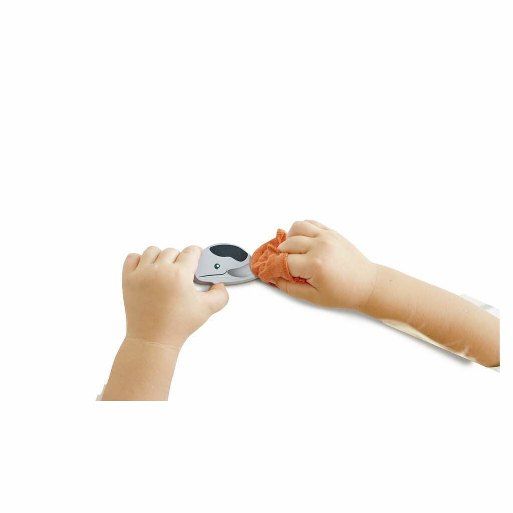 Manos de niño limpian un juguete de ballena con un paño naranja.