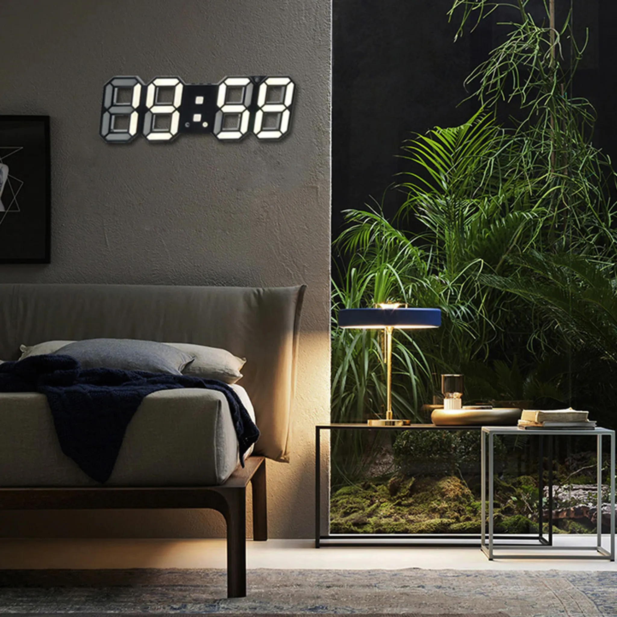 Modernes Schlafzimmer mit Digitaluhr, Bett, Lampe und Pflanzen.
