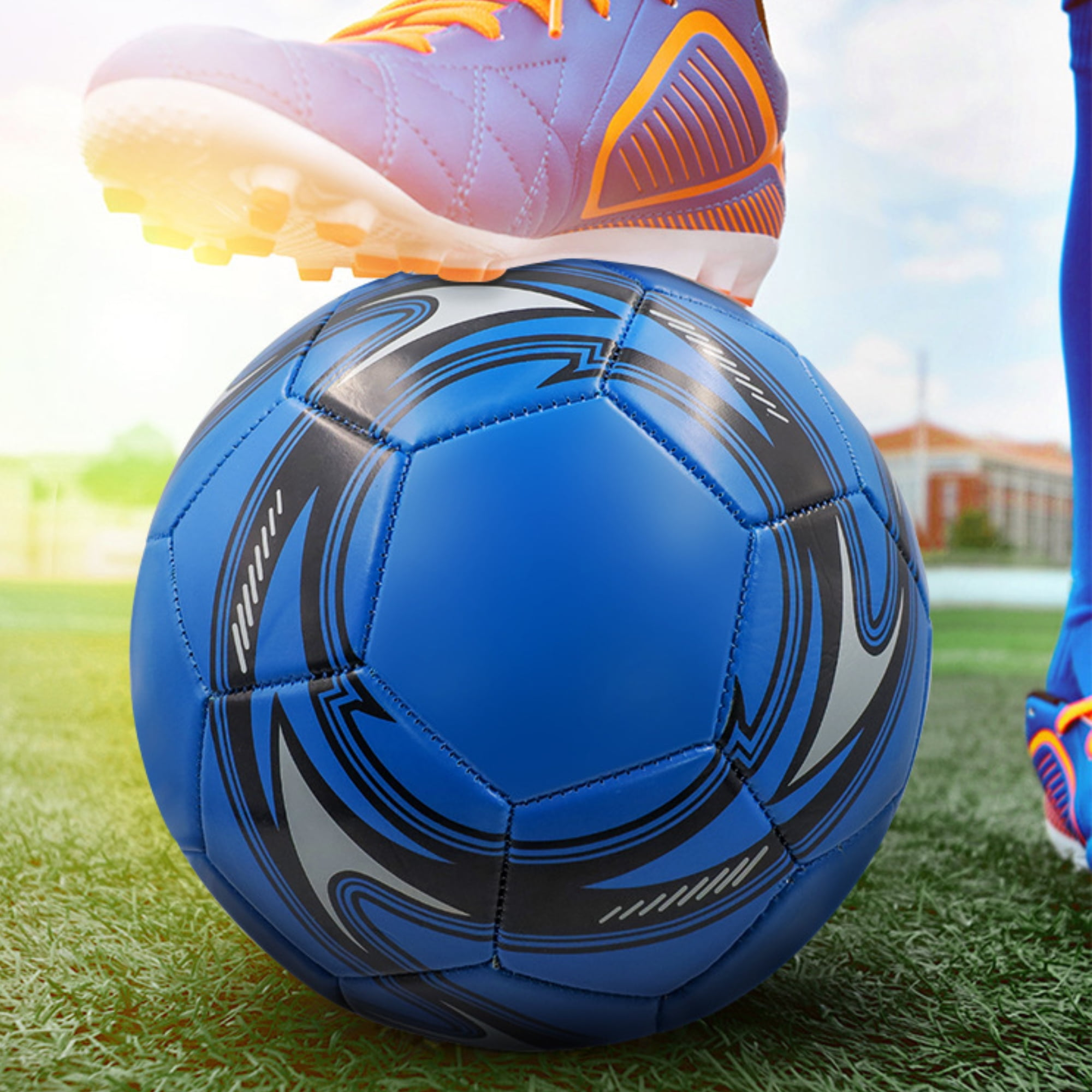 Ein blauer Fußball mit schwarzen und grauen Verzierungen liegt auf Kunstrasen. Ein Fußballschuh ist darüber.