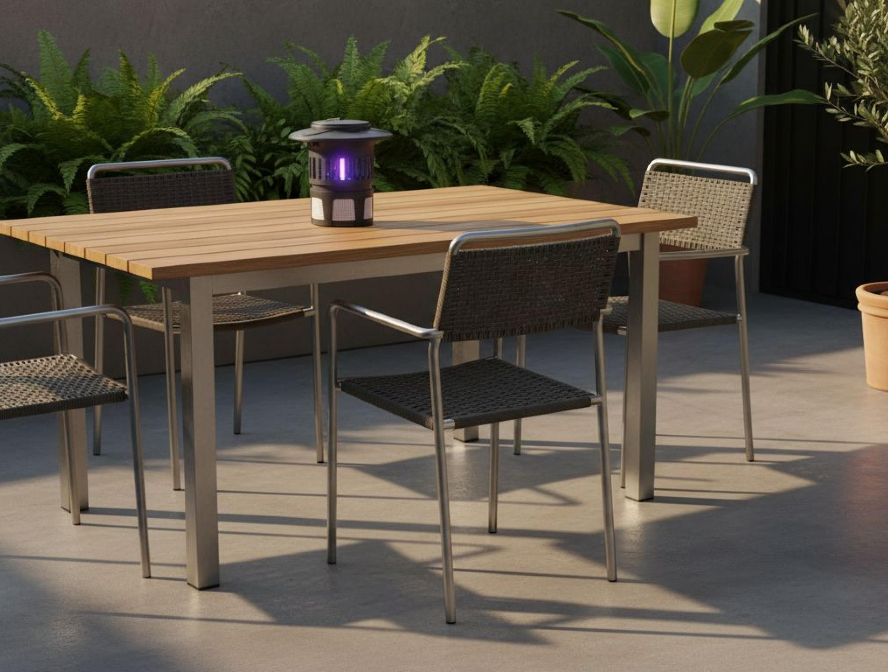 Una mesa de madera con una lámpara antimosquitos oscura está en un patio con sillas.