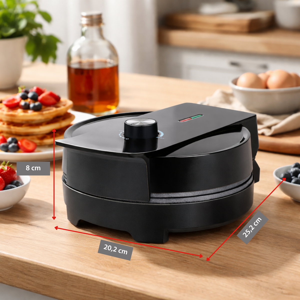 Black waffle maker with dimensions, next to it waffles with fruit.