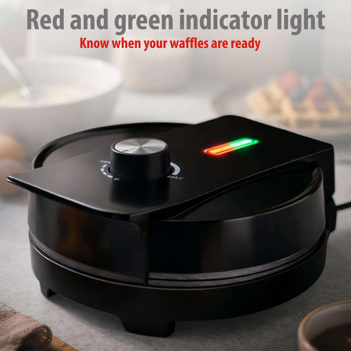 Black waffle maker with red and green indicator lights. Waffles in background.