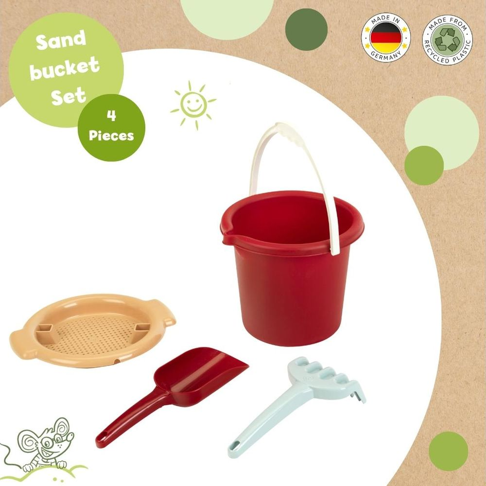 Ein roter Eimer, eine Schaufel, ein Rechen und ein Sieb für den Sandkasten.