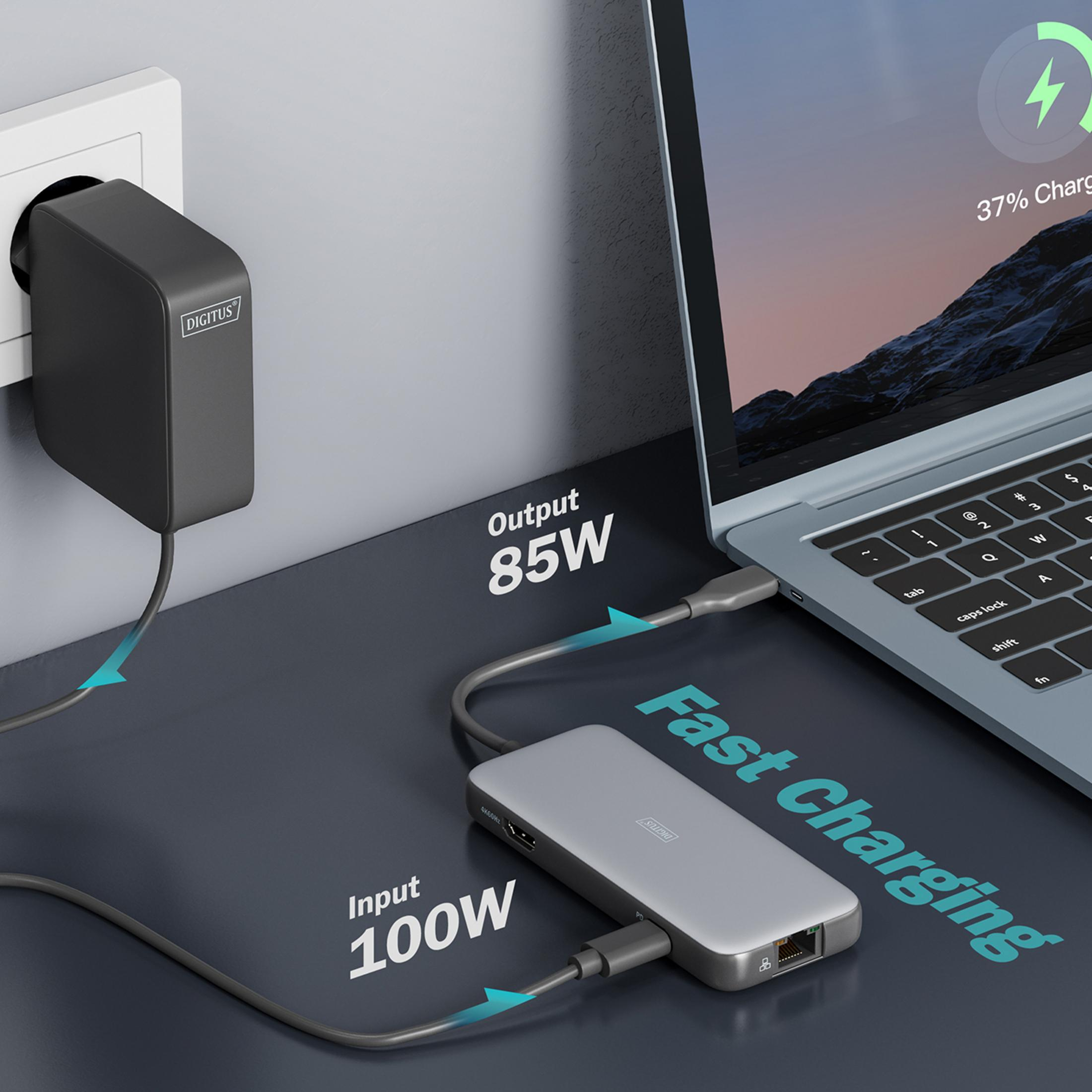 Un alimentatore nero carica un laptop tramite un hub grigio.