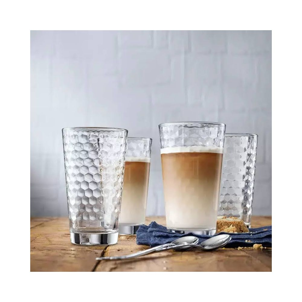 Ahşap masa üzerinde petek desenli dört bardak. Birinde latte var.