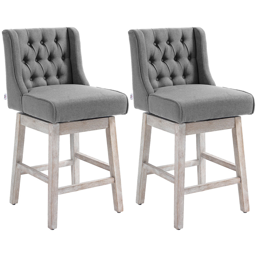 Dos taburetes giratorios tapizados en gris con respaldo capitoné y patas de madera clara.