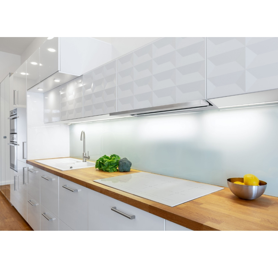 Cucina moderna bianca con piano in legno, lavello, fornelli e ciotola frutta.