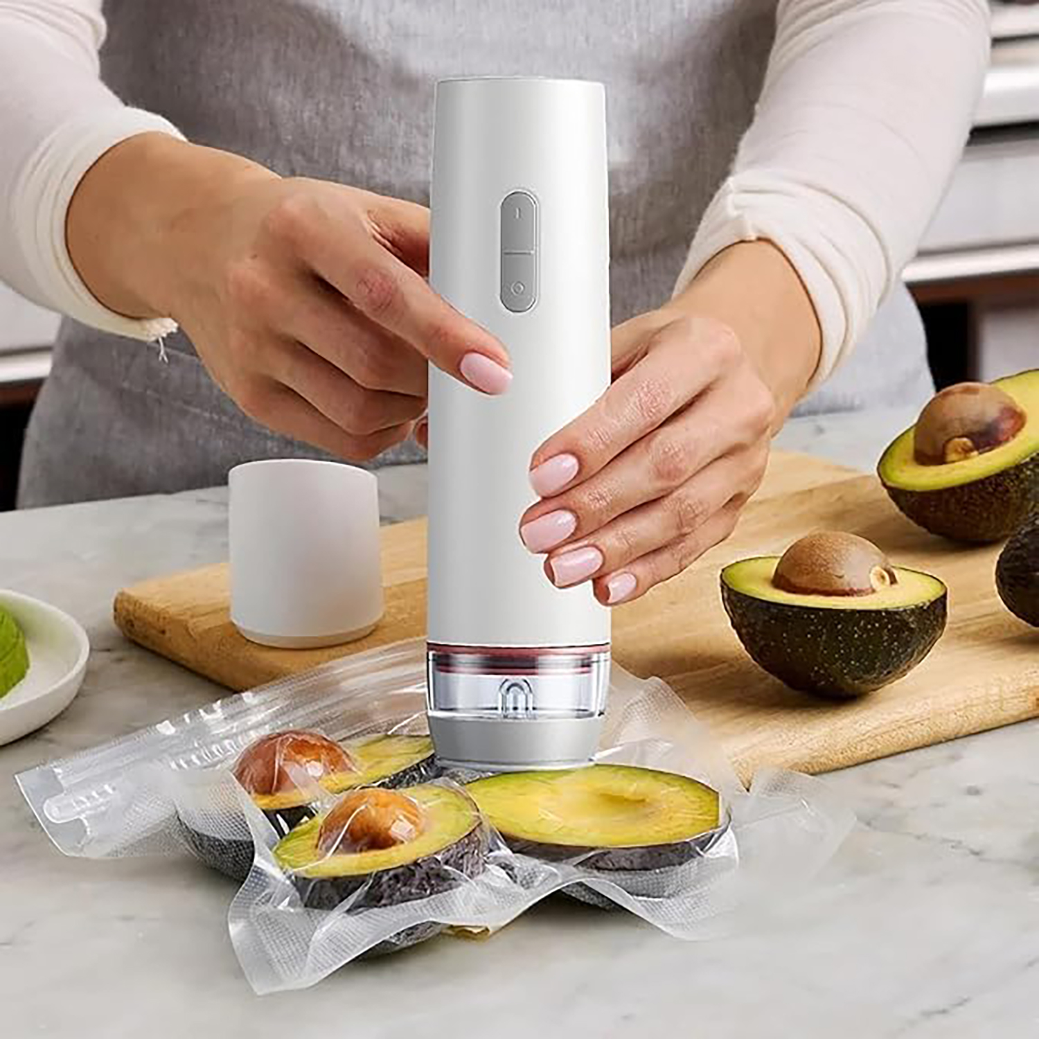 Eine Person vakuumversiegelt Avocados mit einem weißen Gerät.