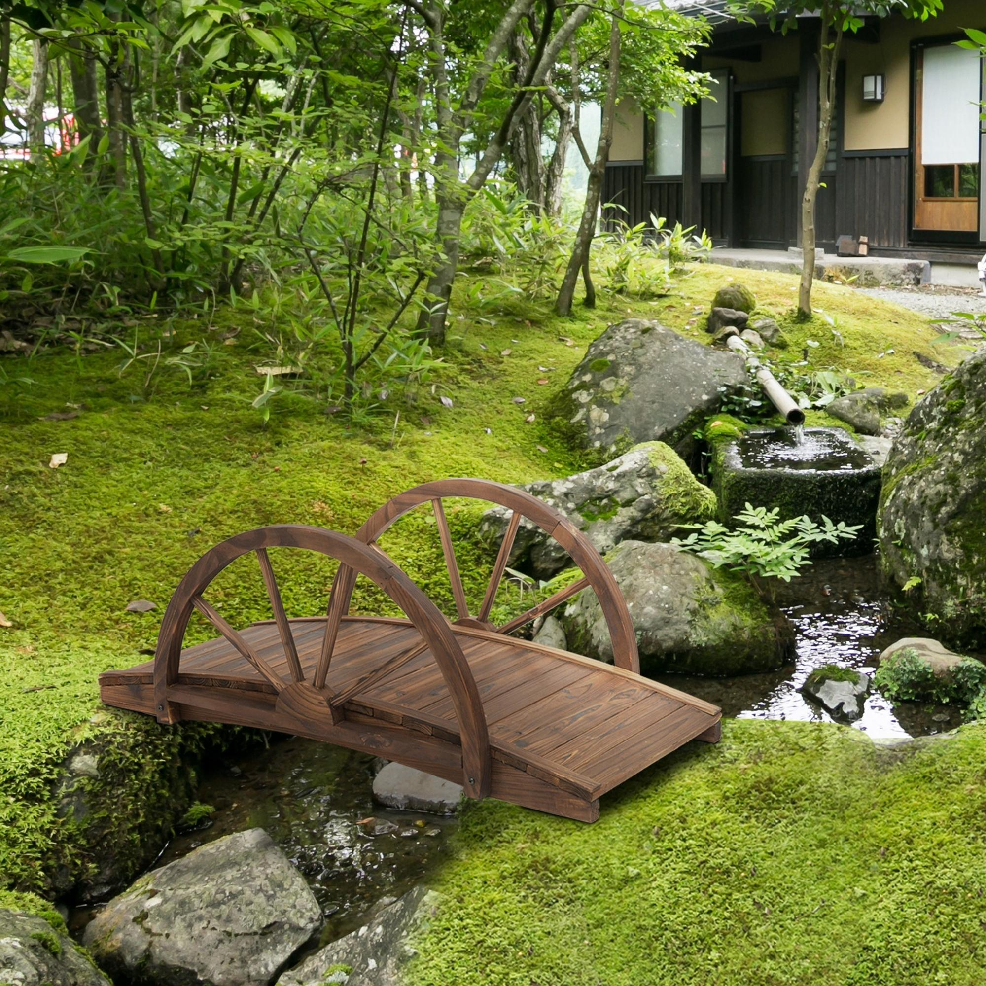 Un puente de madera cruza un arroyo cubierto de musgo en un jardín japonés.