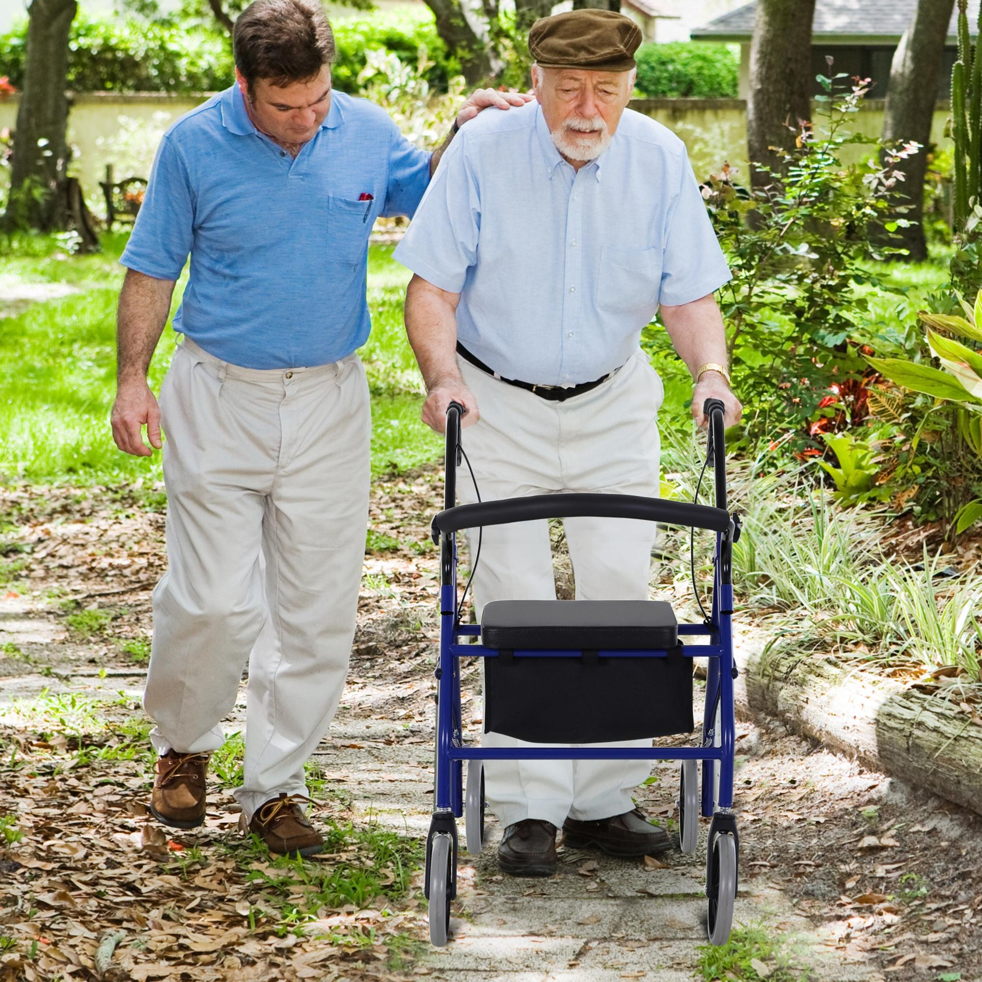 Un hombre apoya a un anciano con andador en un camino de jardín.