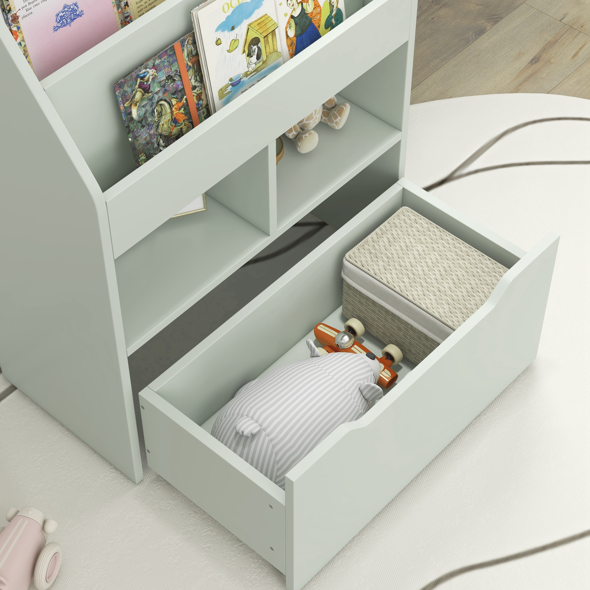 Una estantería verde claro tiene libros, juguetes y una cesta. Un cajón contiene una almohada a rayas y un monopatín de juguete.