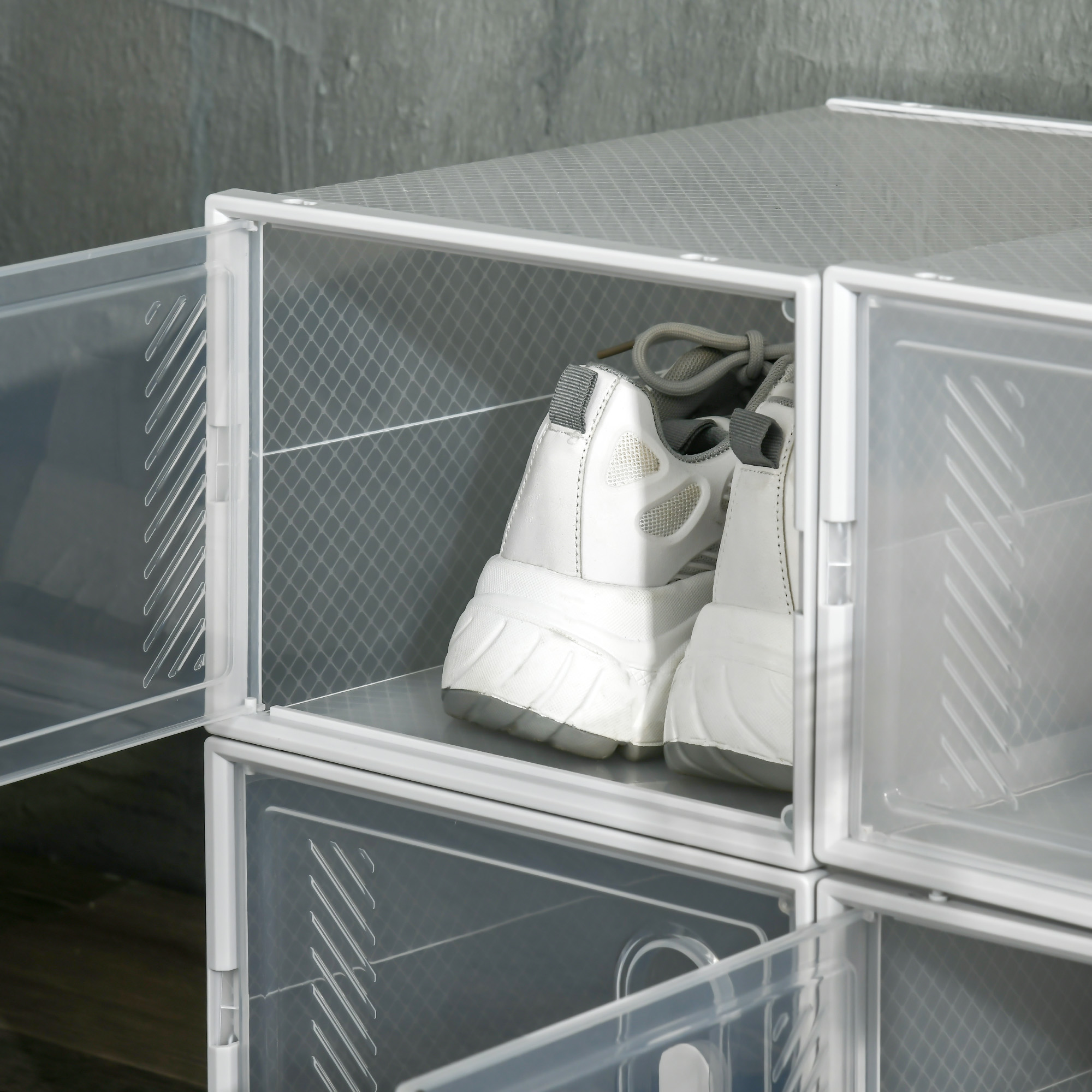 Zapatillas blancas en cajas de zapatos transparentes apiladas.