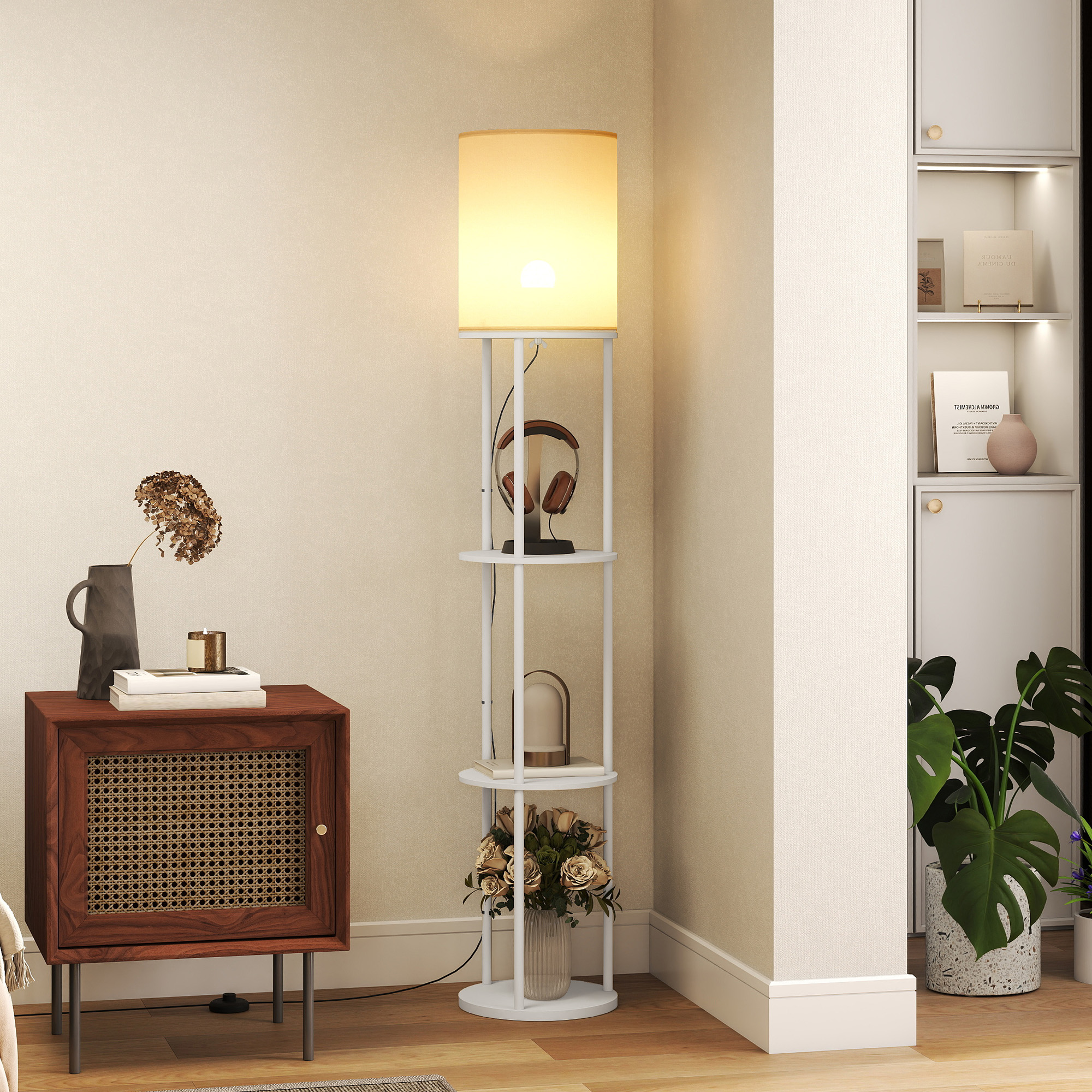 Una estantería blanca con lámpara, auriculares, libros y flores.