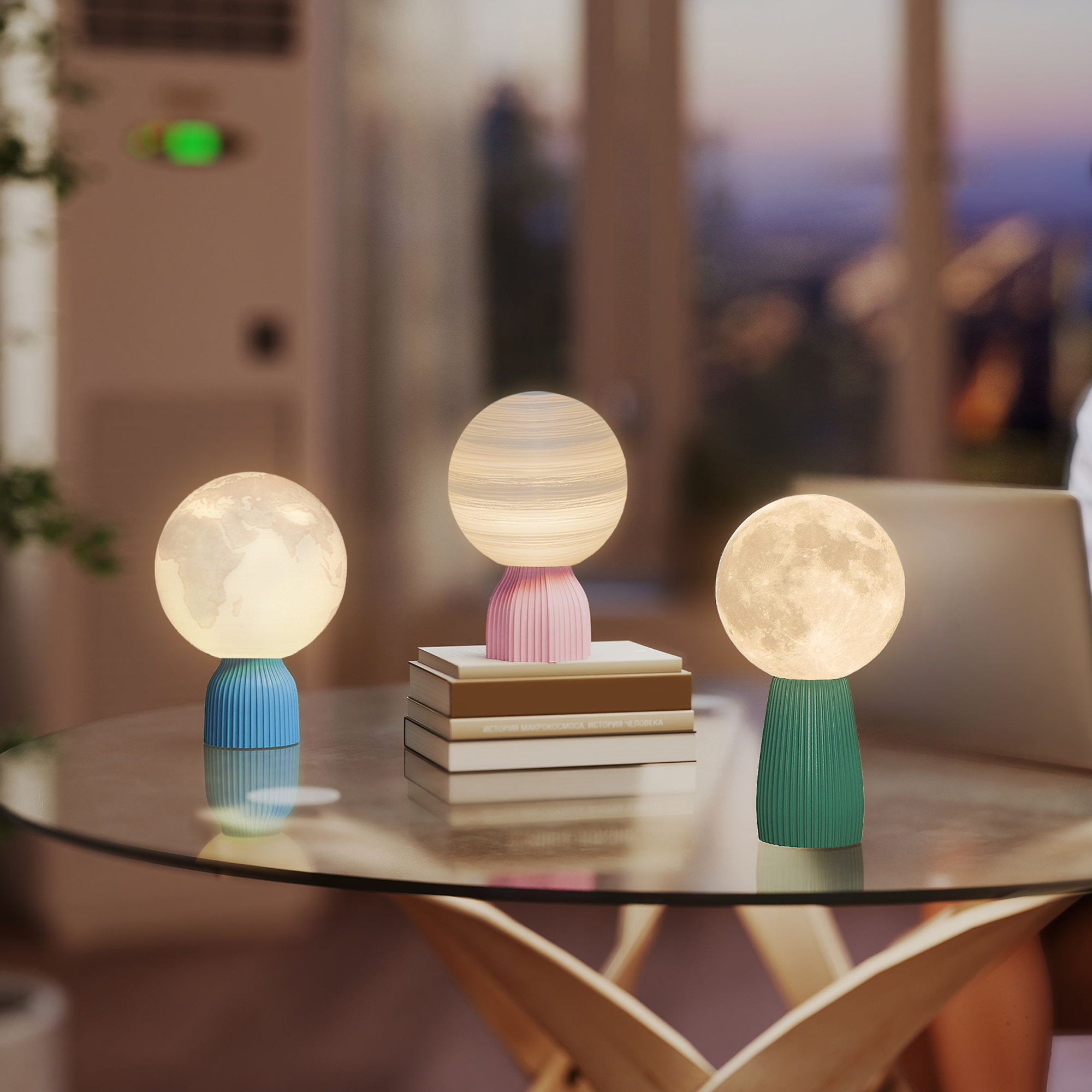 Tres lámparas decorativas sobre una mesa de cristal: un globo, una rayada y una de luna.