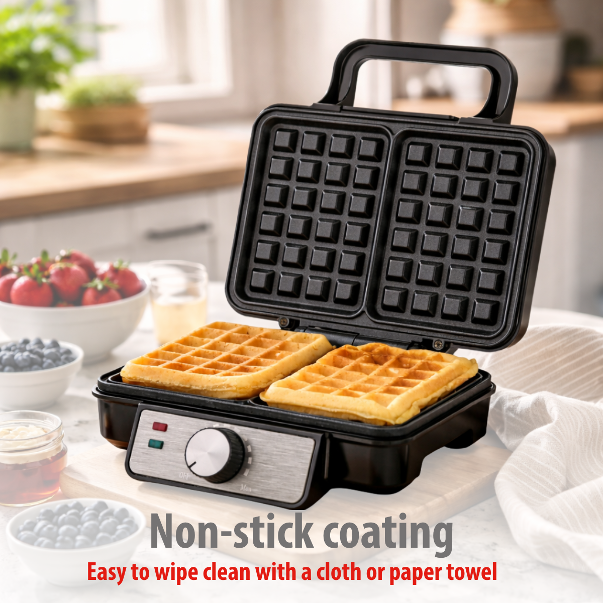 An open waffle maker with two golden waffles and berries in the background.