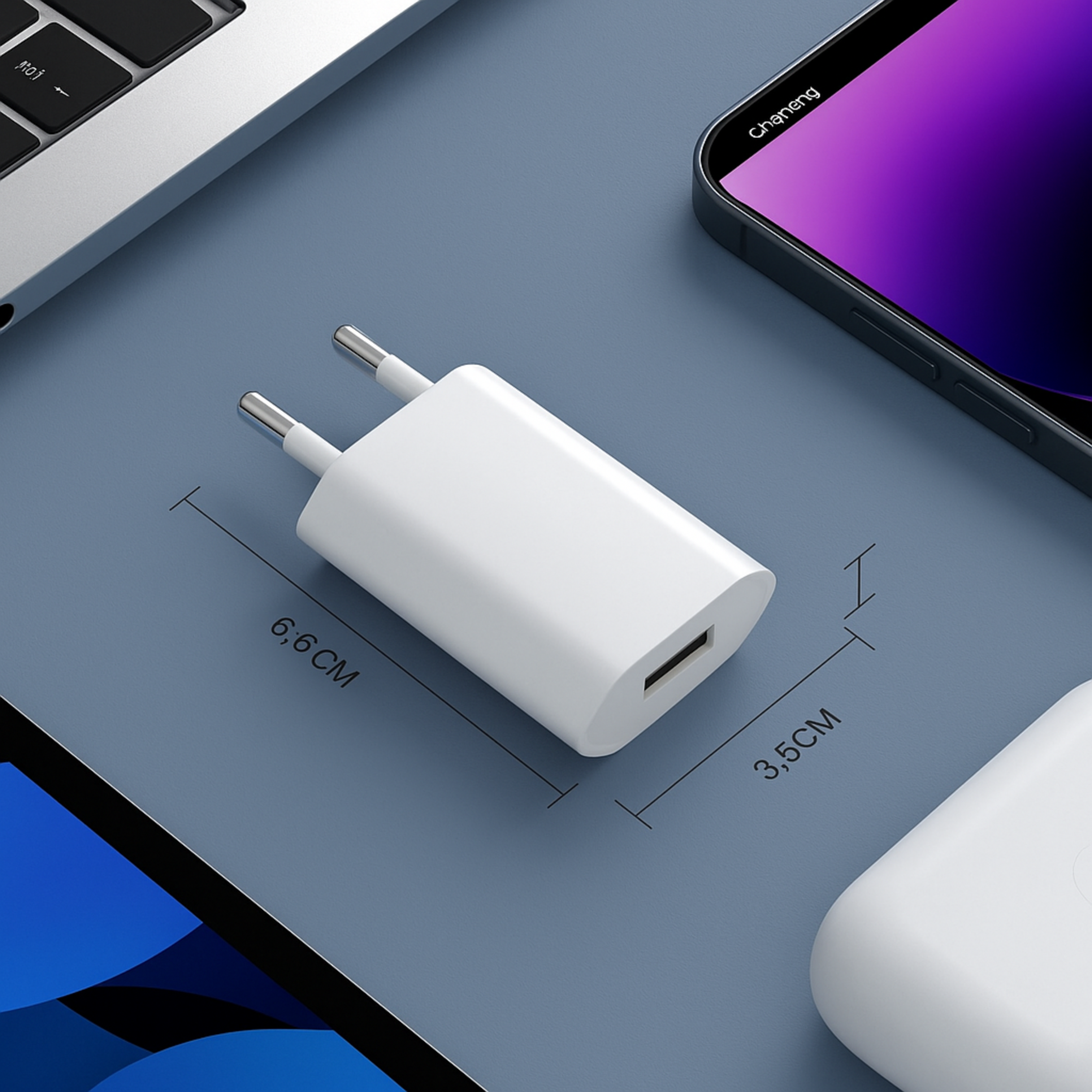 Weißer USB-Ladestecker mit Metallstiften, neben einem Smartphone und Laptop.