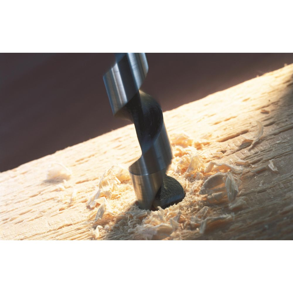 Ein Holzbohrer bohrt in ein Holzbrett und hinterlässt Späne.