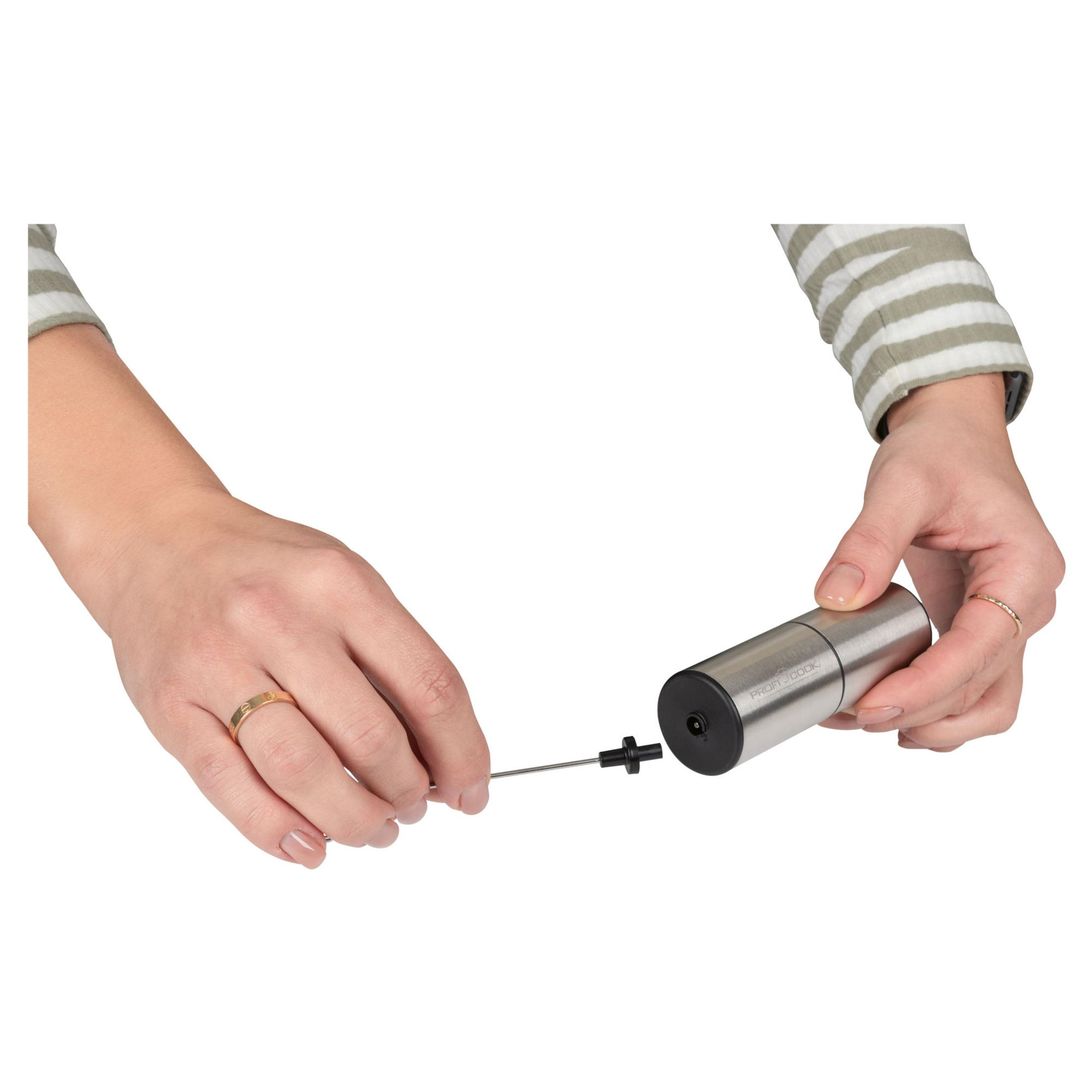 Ręce składają srebrny młynek z czarną nakładką i cienkim prętem.