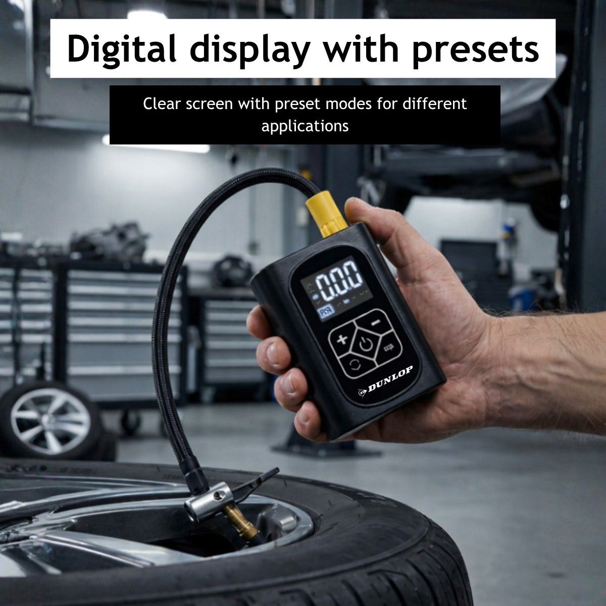 Een hand houdt een zwarte Dunlop bandenspanningsmeter met slang vast aan een autoband.