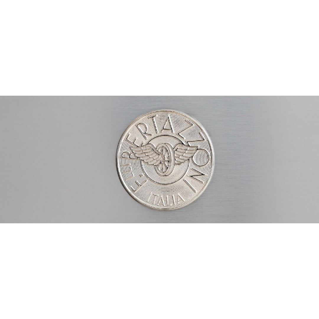 Un emblema circolare argentato con ruota alata e scritta "FERT ZON ITALIA".