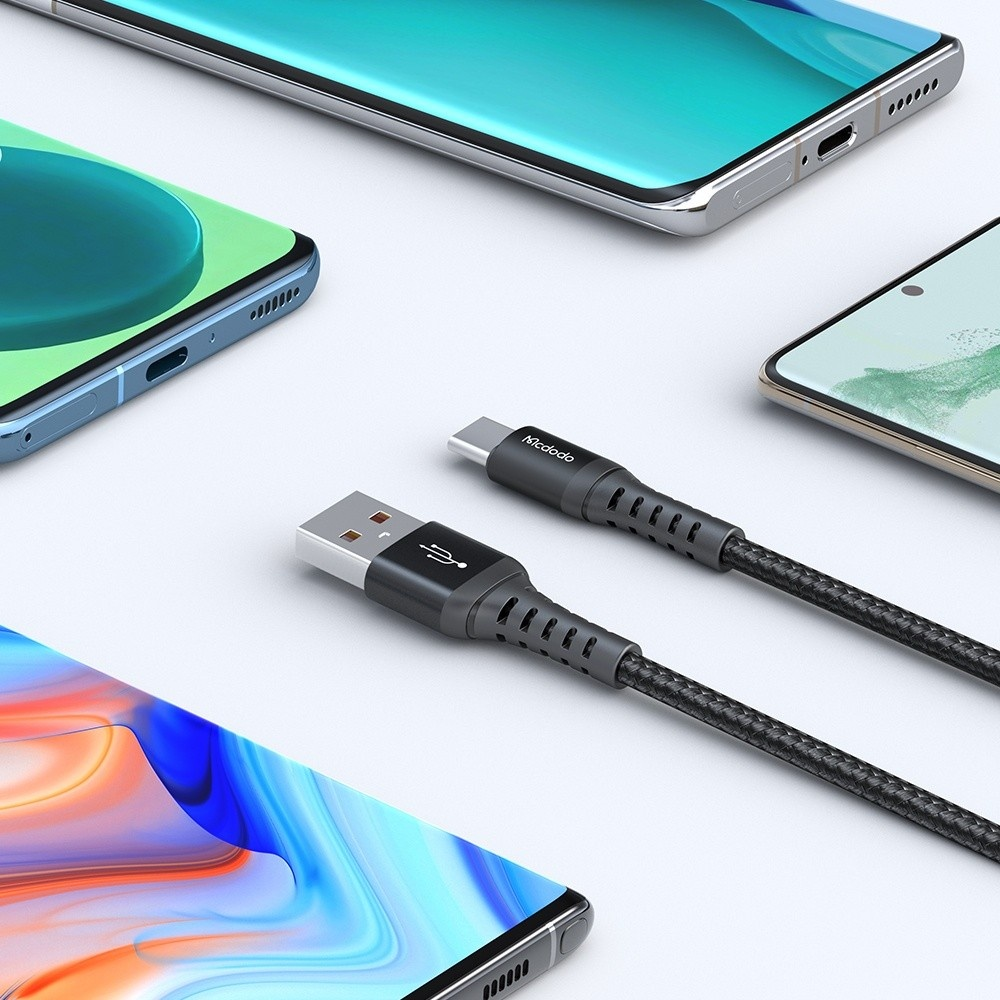 Bir USB-C şarj kablosu üç modern akıllı telefonun yanında duruyor.