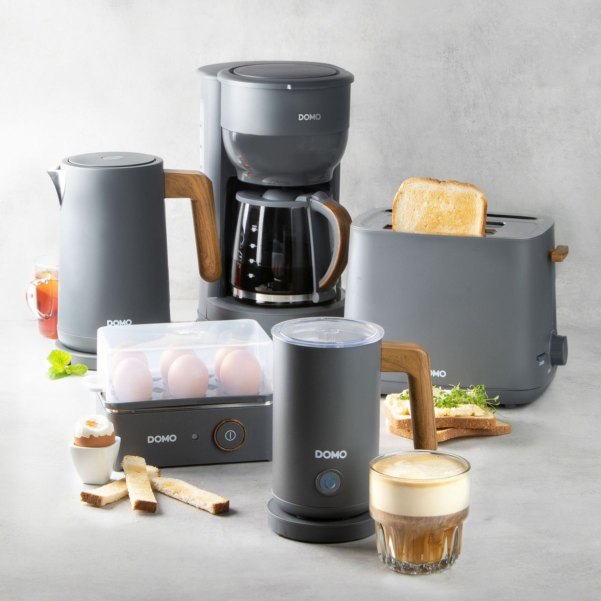 Graue Küchengeräte für Frühstück: Kaffeemaschine, Toaster, Eierkocher, Milchaufschäumer, Wasserkocher.