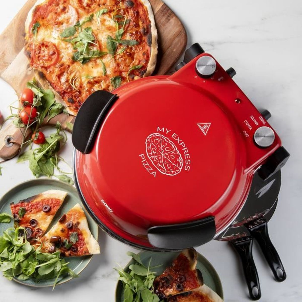 Un four à pizza rouge avec deux assiettes de pizza et des tomates cerises à côté.