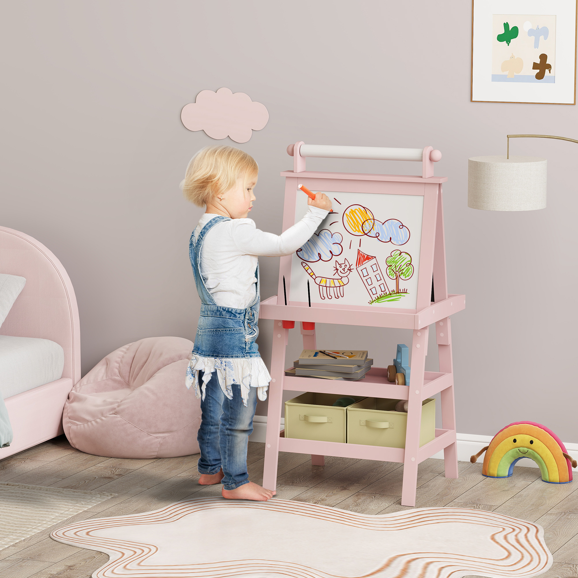 Un niño rubio con peto vaquero dibuja en un caballete rosa en una habitación infantil.