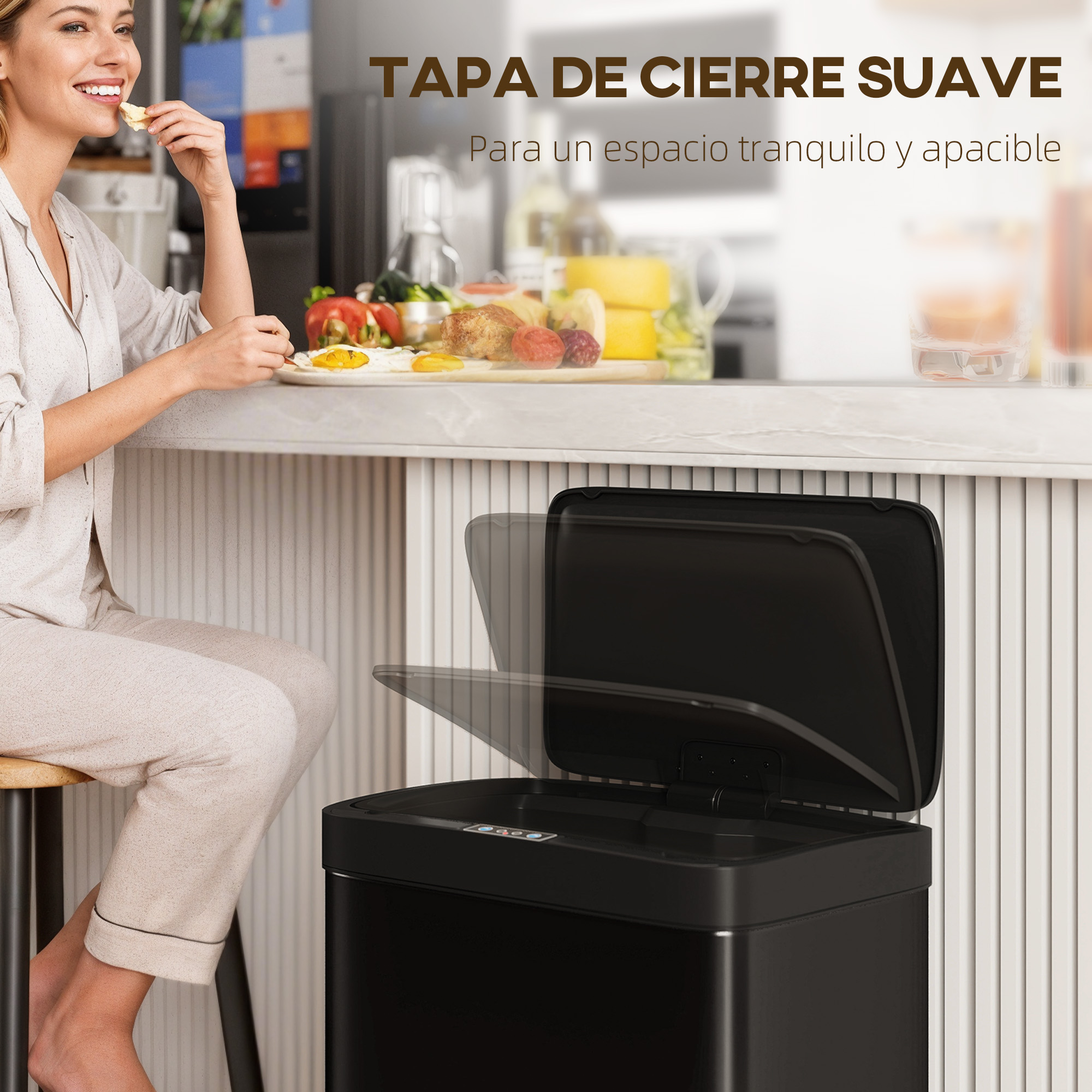 Una mujer desayuna junto a un cubo de basura negro abierto en una cocina moderna.