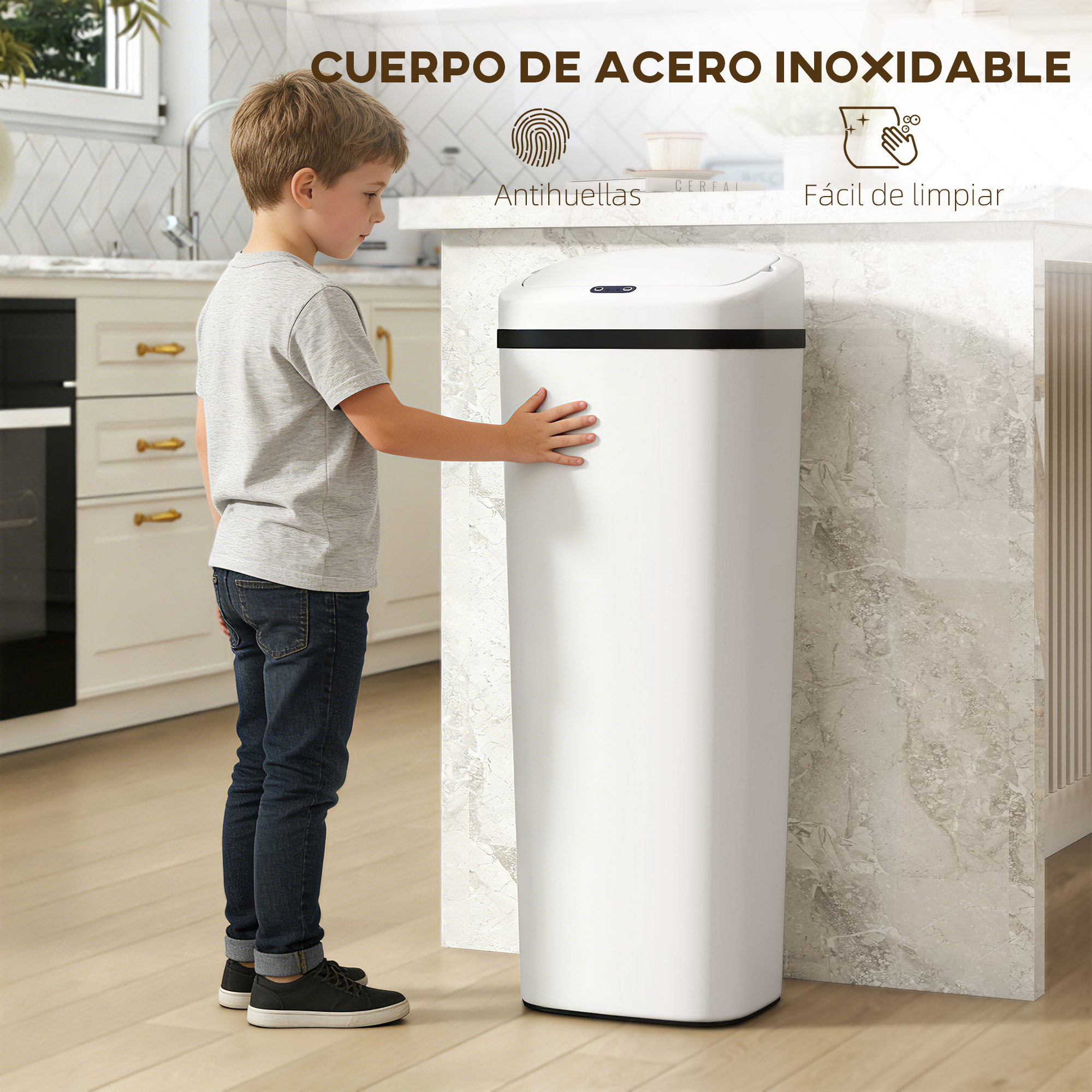 Un niño con jeans y camiseta toca un cubo de basura blanco en una cocina.