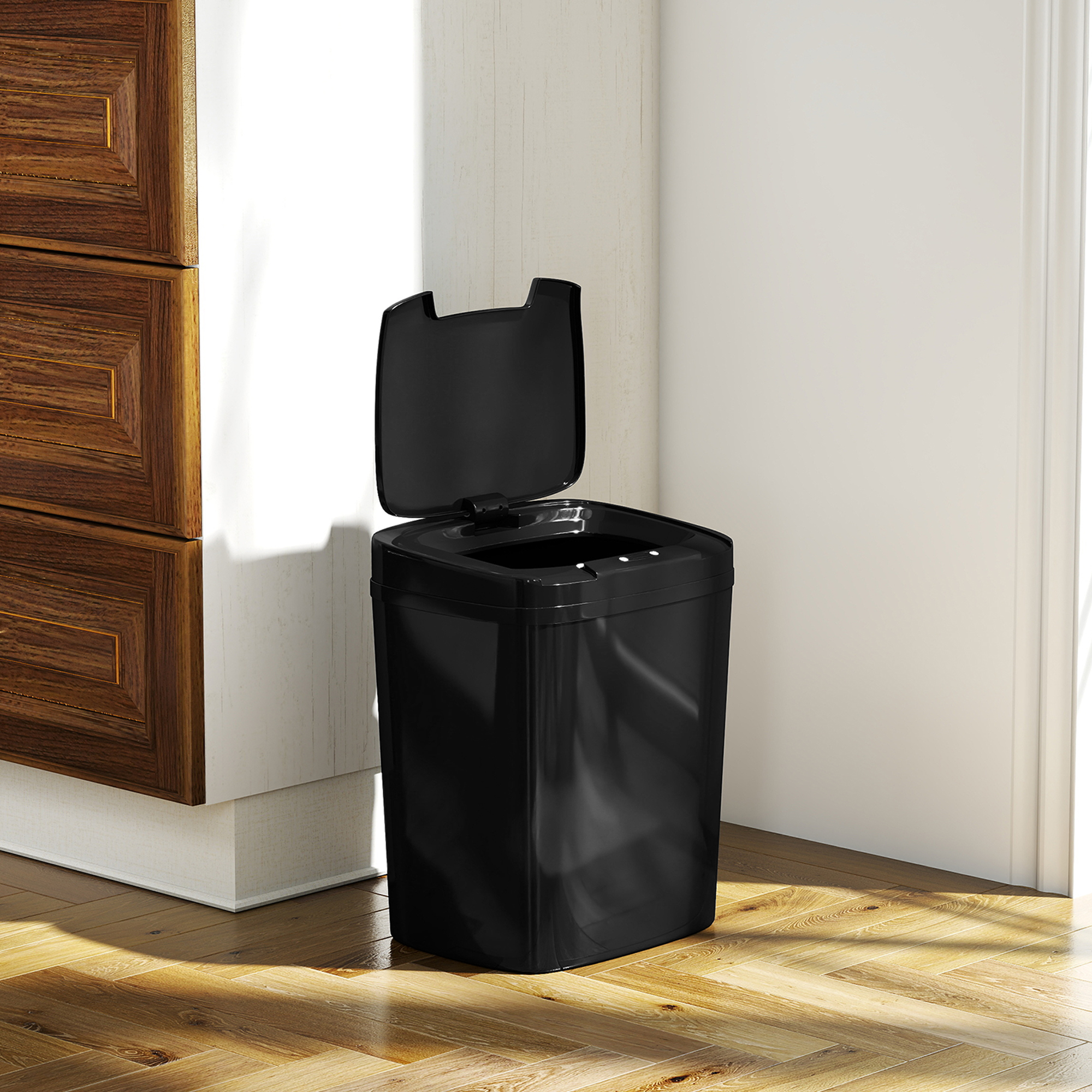 Un cubo de basura negro con la tapa abierta está sobre un suelo de madera.