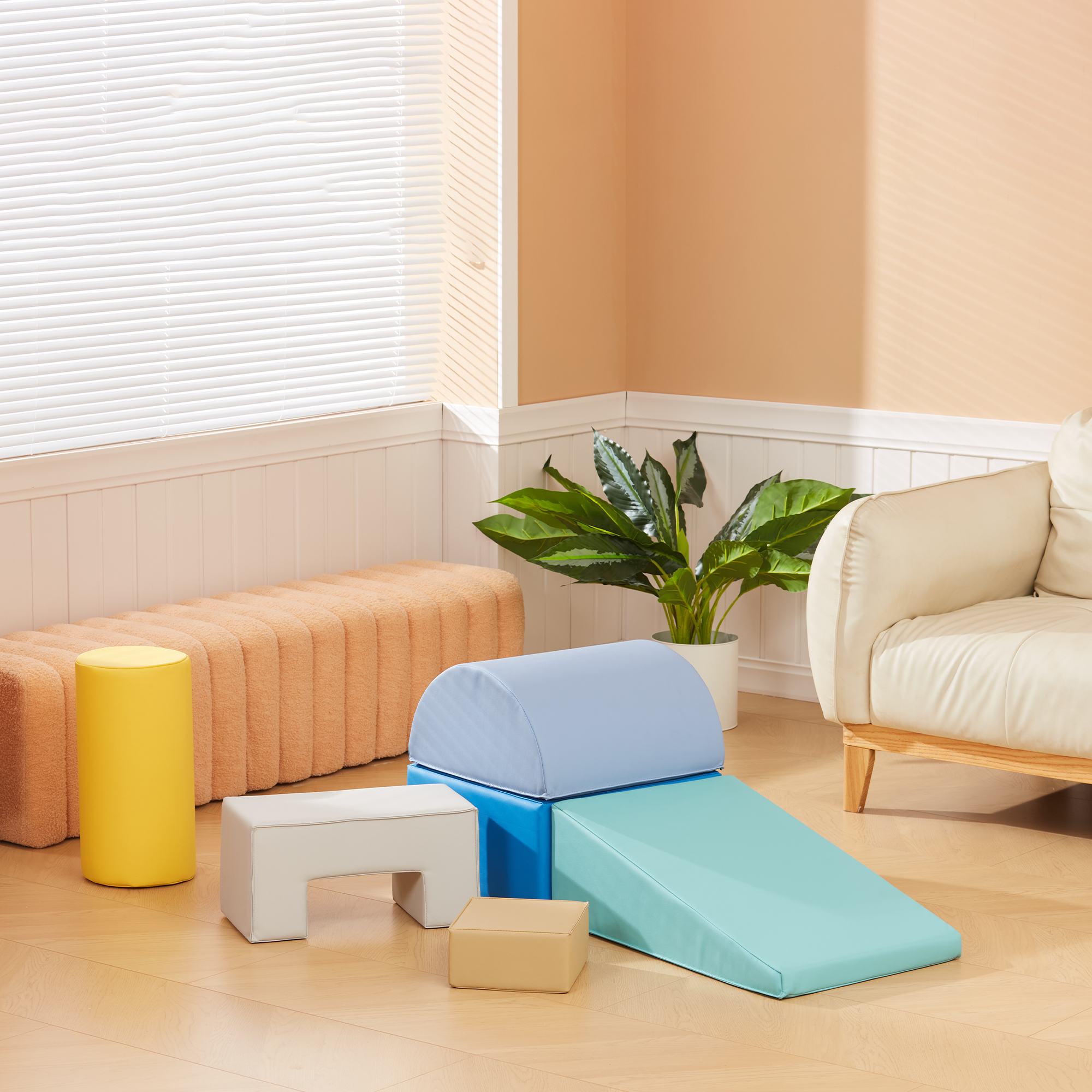 Una sala de estar con equipo de juego infantil: taburete amarillo, sofá naranja, rampa azul.