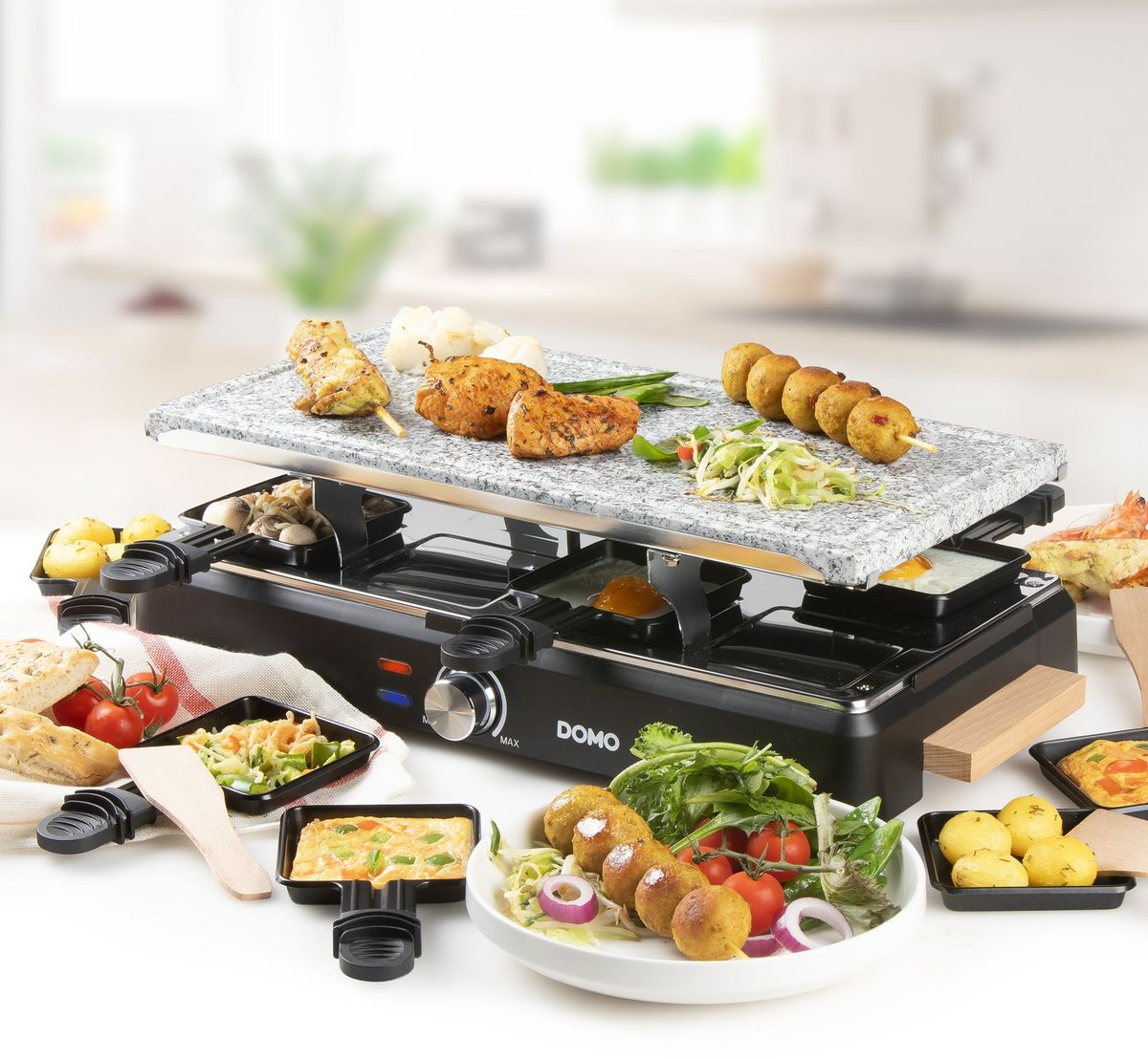 Ein Raclette-Grill mit Steinplatte, gefüllt mit Fleisch, Kartoffeln, Pilzen und Gemüse.